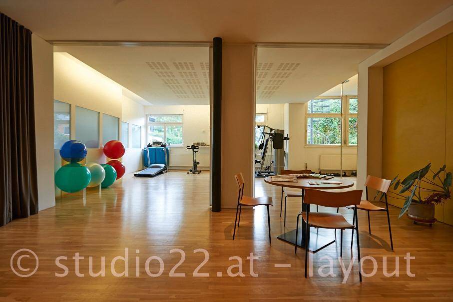 Großer Mehrzweckraum, der einen Fitnessbereich und einen Wartebereich mit Holzboden verbindet.