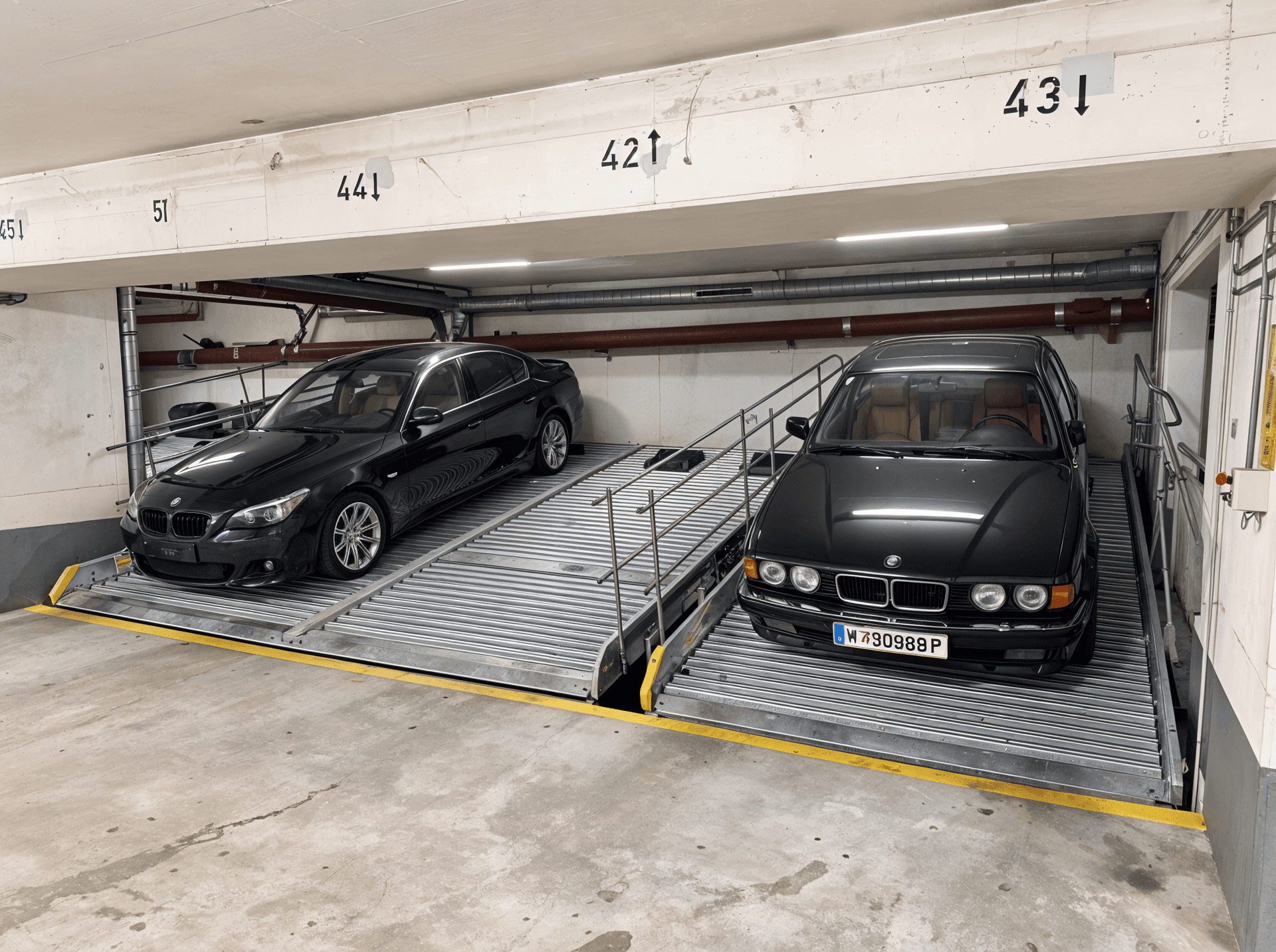 Ansicht der Parkliftsysteme mit zwei geparkten Fahrzeugen in der Tiefgarage.