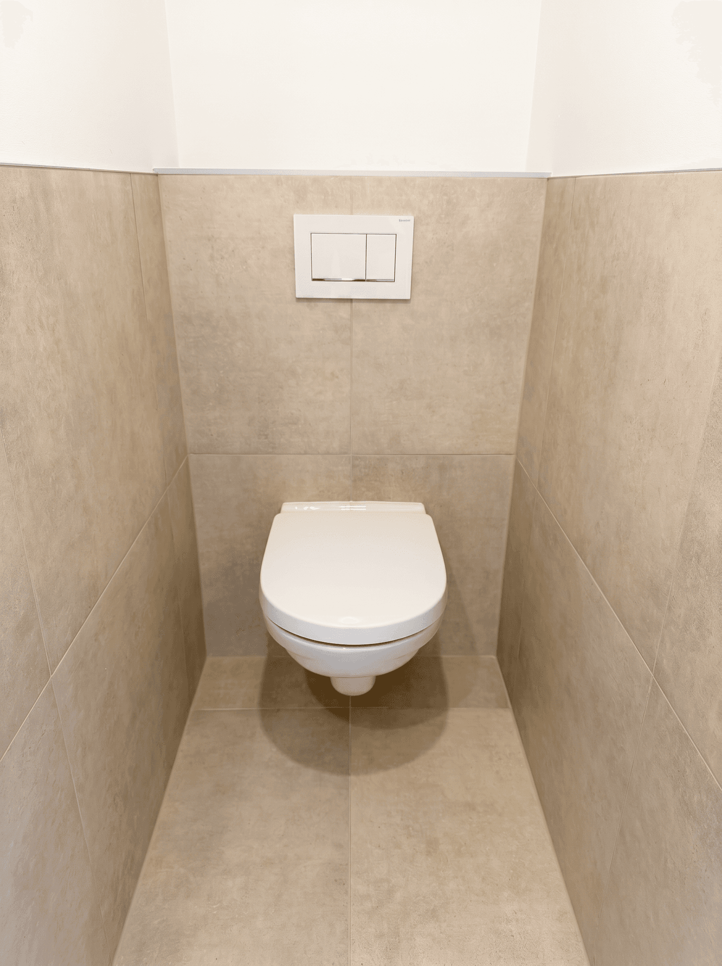 Separates WC mit wandhängender Toilette und beigefarbenen Fliesen, modern und funktional.