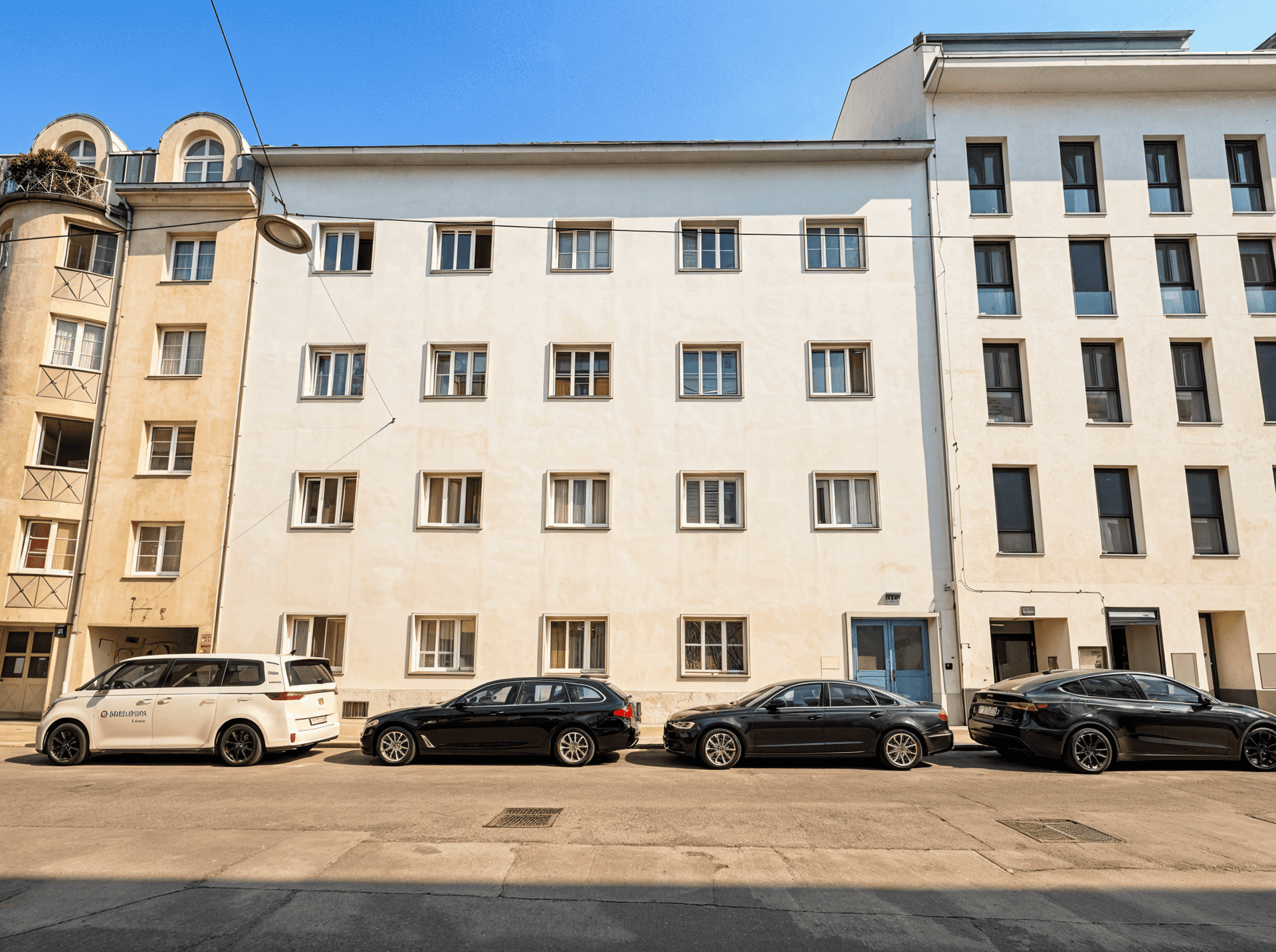 Klassische Fassade eines Wohngebäudes an einer Straße mit geparkten Autos.