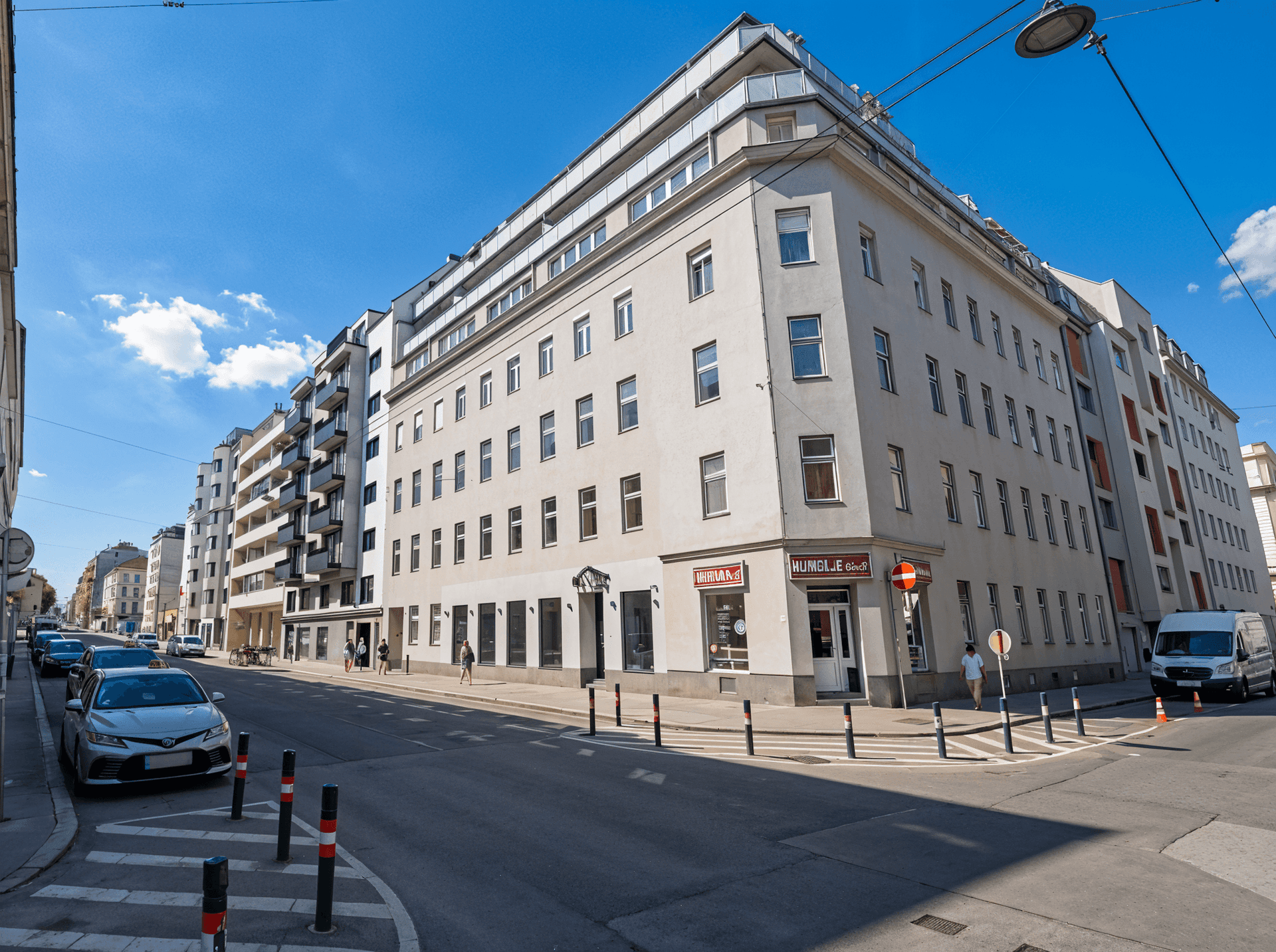 Eckgebäude in urbaner Umgebung mit Geschäften im Erdgeschoss und blauem Himmel.