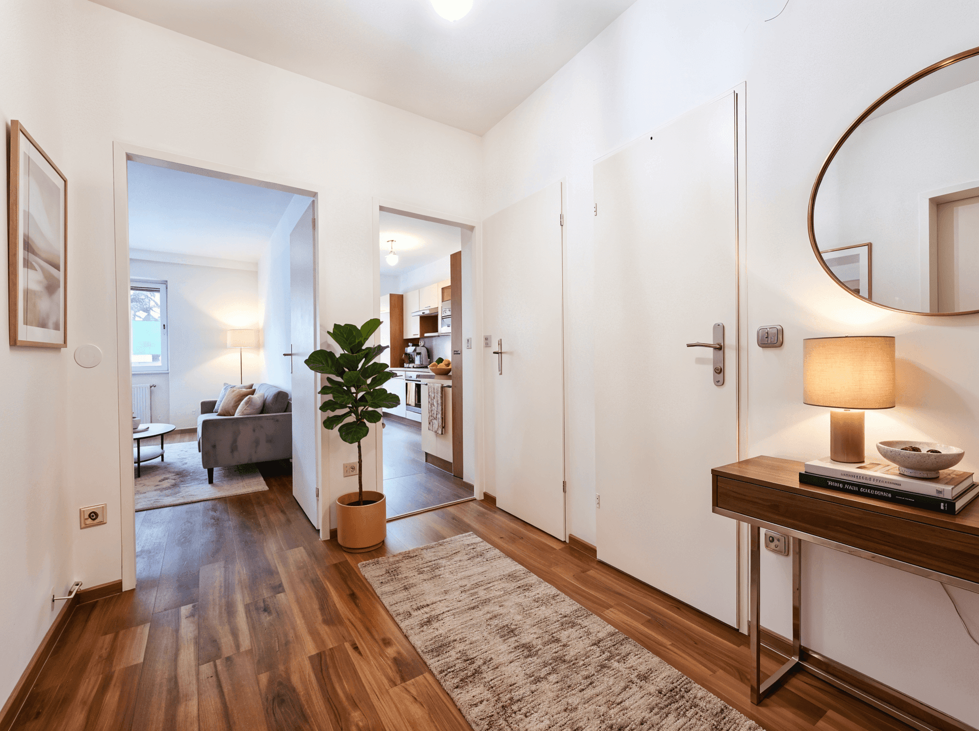 Heller Flur mit Holzboden, Spiegel und Zugang zu Wohnzimmer und Küche.