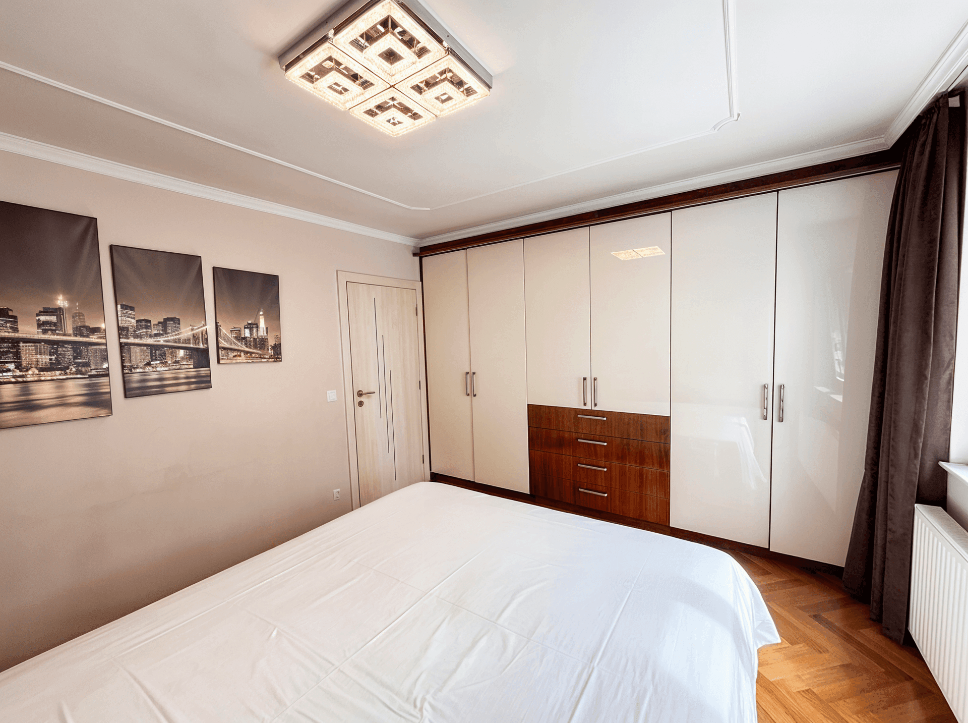 Schlafzimmer mit Einbauschränken, Parkettboden und moderner Wanddekoration.