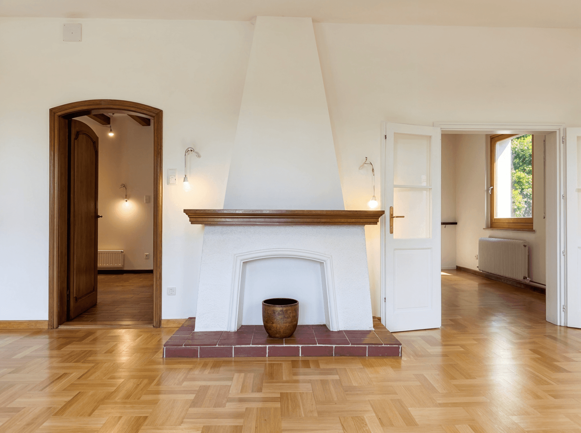 Detailansicht des Kamins mit Terrakotta-Fliesen und Holzbalken in einem hellen Wohnzimmer.