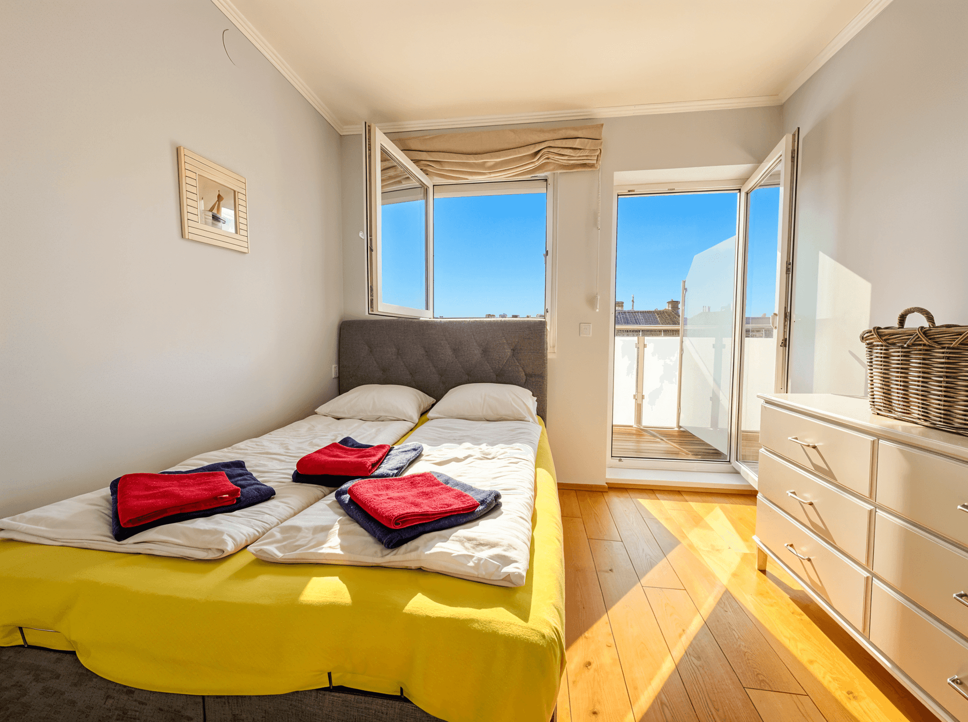 Helles Schlafzimmer mit zwei Einzelbetten, Holzboden und direktem Zugang zum Balkon.