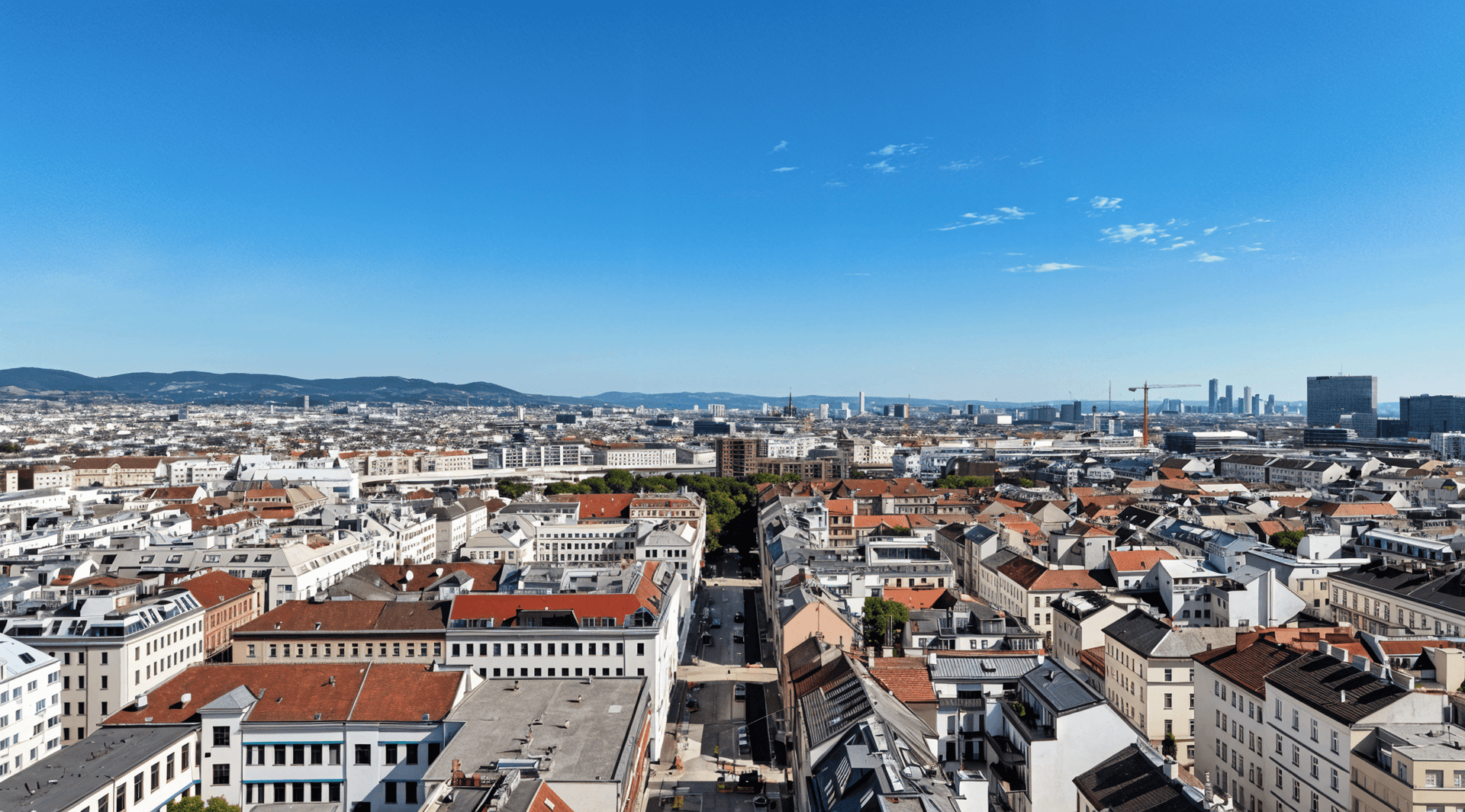 Panoramablick über die Stadt mit vielen Dächern und Bergen im Hintergrund.