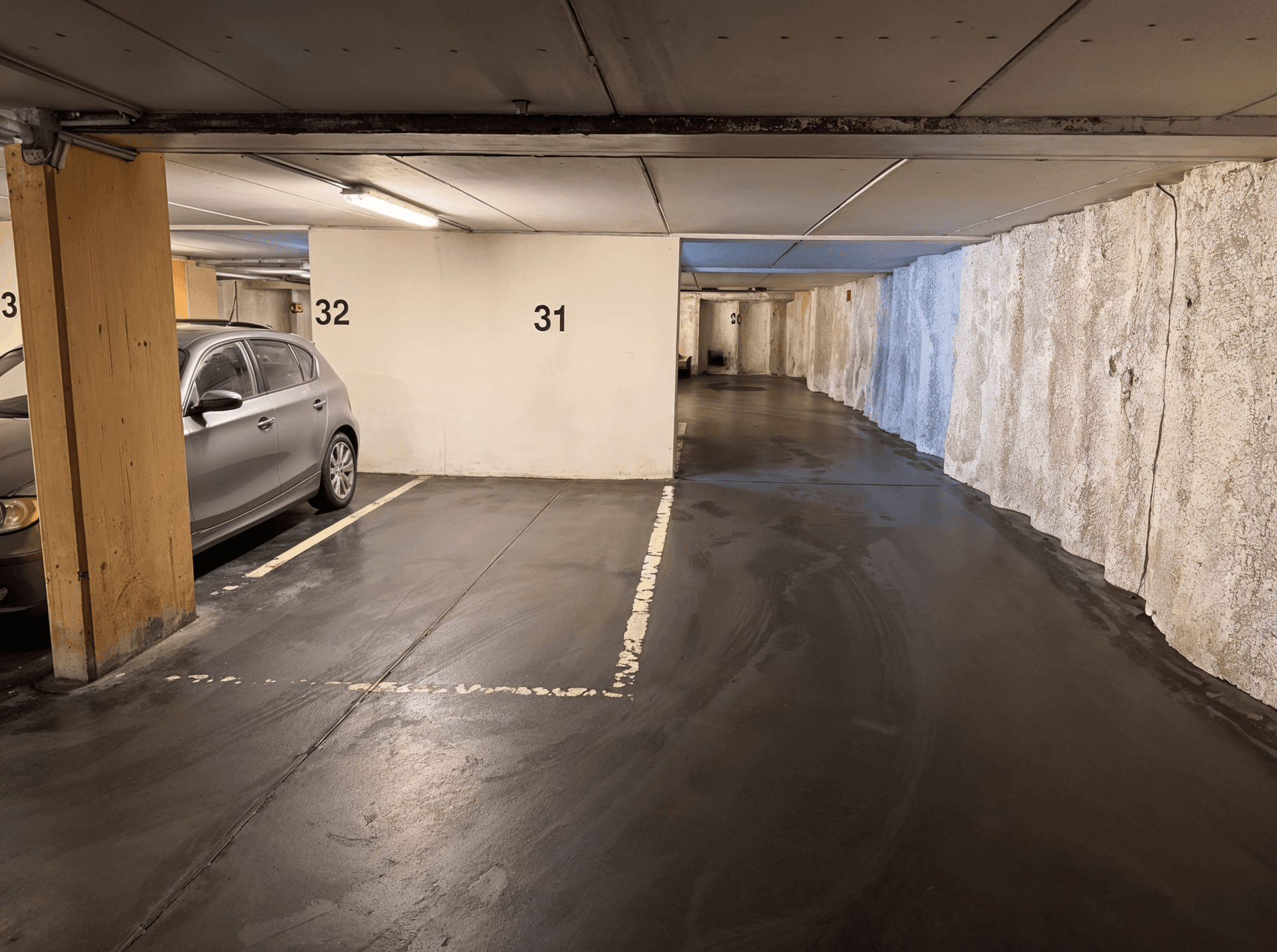 Geräumige Tiefgarage mit mehreren Stellplätzen und einem geparkten Fahrzeug, gut beleuchtet.
