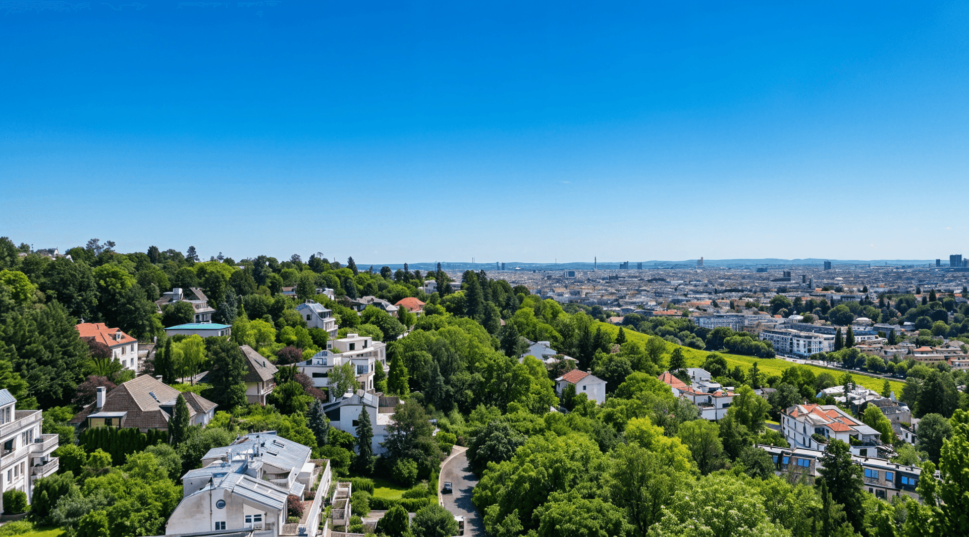 Panoramablick über eine grüne Wohngegend mit vielen Häusern und der Stadt im Hintergrund.