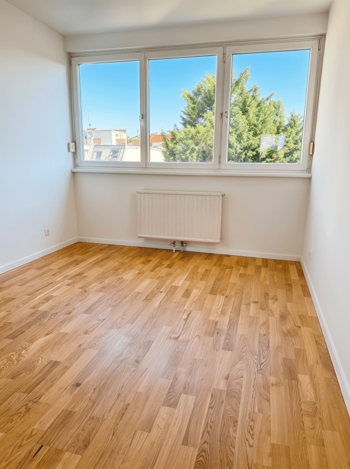 Heller Raum mit großen Fenstern, Parkettboden und viel Tageslicht, ideal für ein Schlafzimmer.