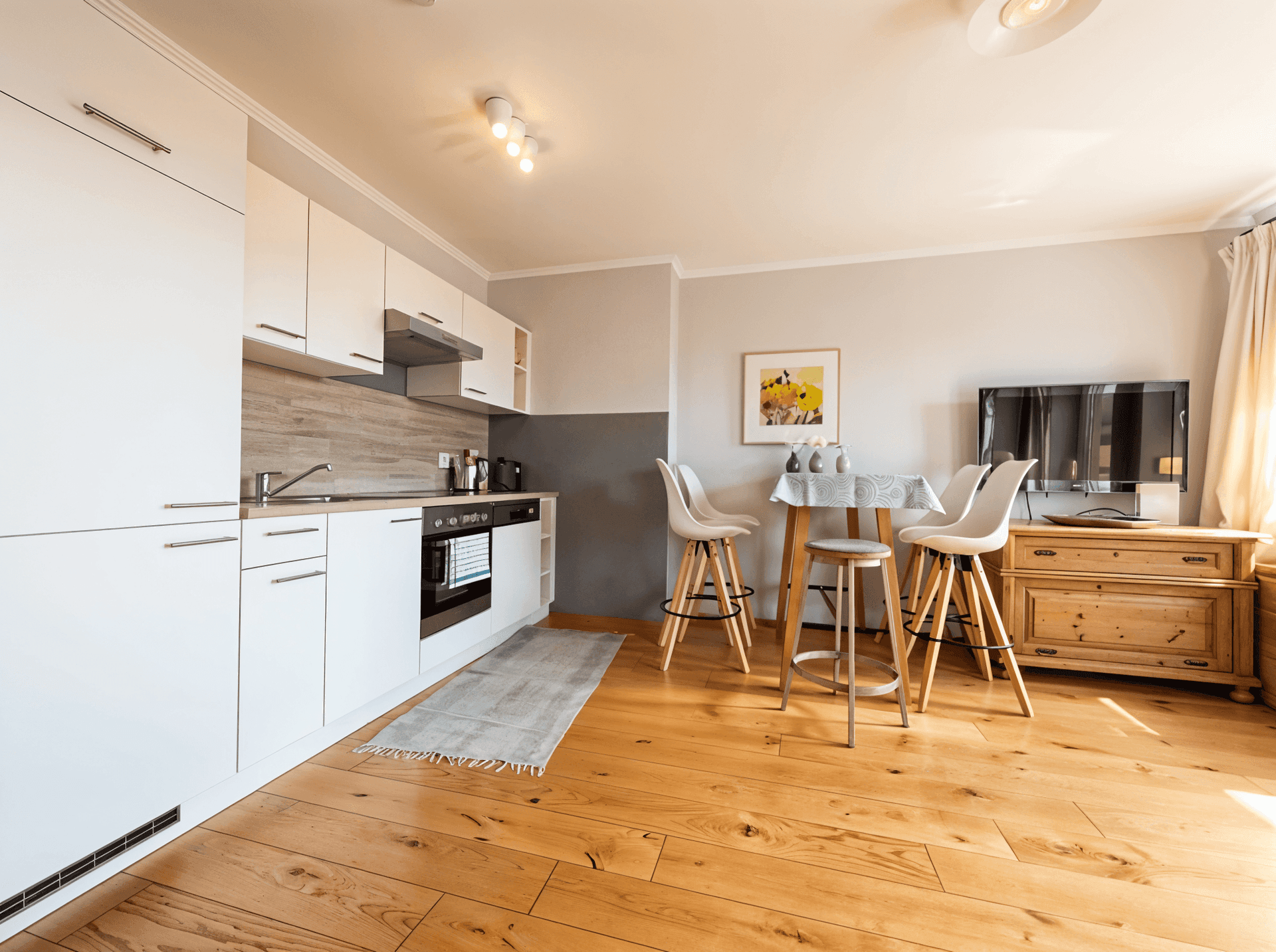 Moderne Einbauküche mit weißen Schränken, Holzboden und integrierten Geräten.