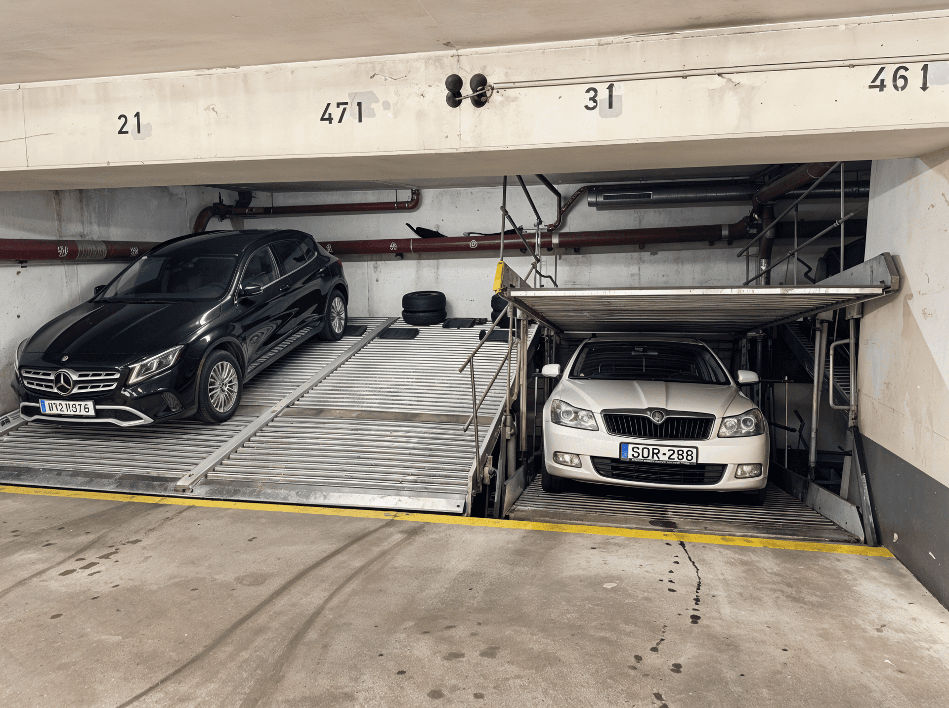 Zwei Fahrzeuge auf einem Doppelparker-System in einer gut beleuchteten Tiefgarage.