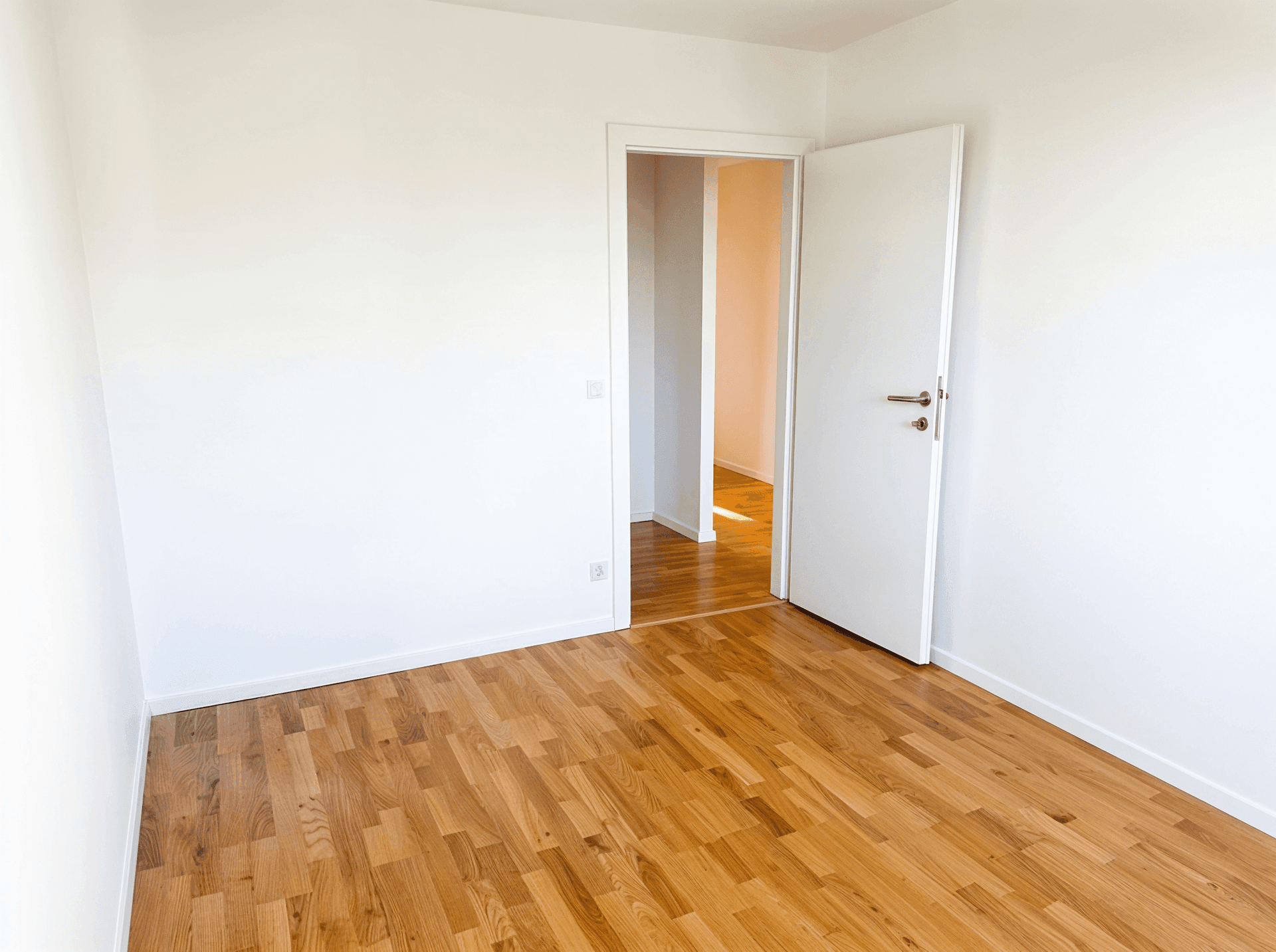 Unmöbliertes Zimmer mit hellem Parkettboden und weiß gestrichenen Wänden, vielseitig nutzbar.