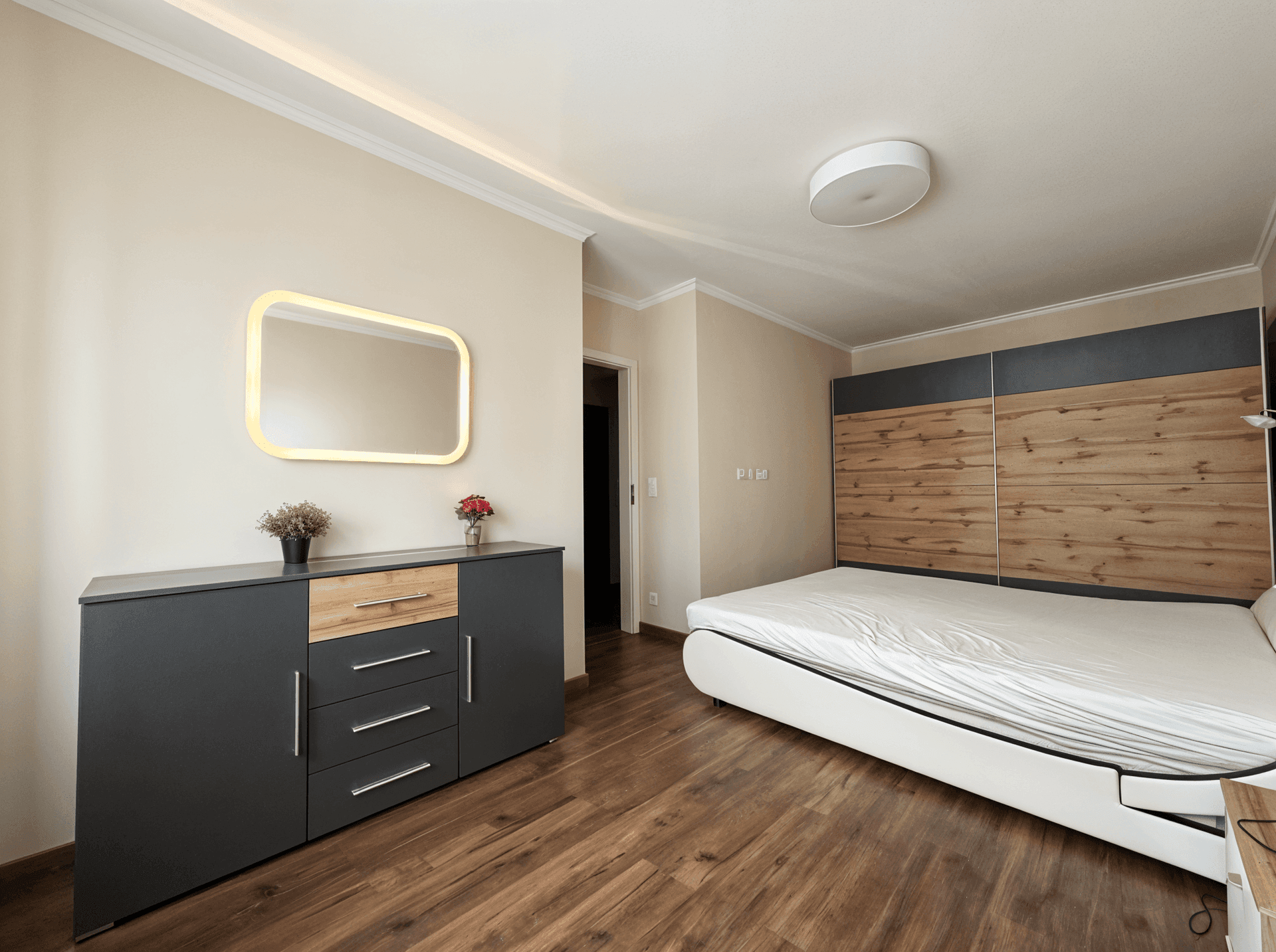 Modernes Schlafzimmer mit Holzboden, großem Bett und stilvoller Kommode.