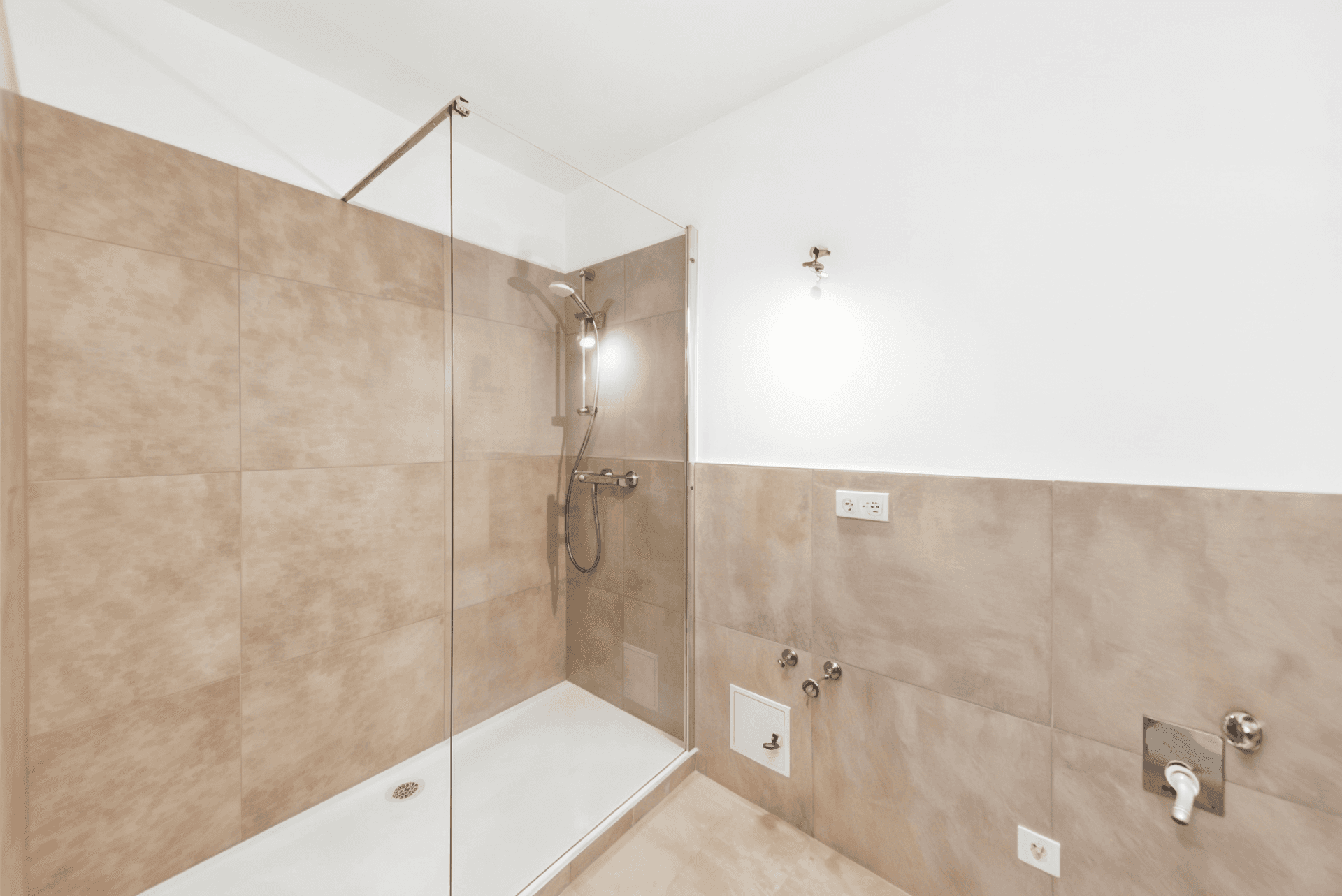 Modernes Badezimmer mit begehbarer Dusche, Glasabtrennung und beigefarbenen Fliesen.