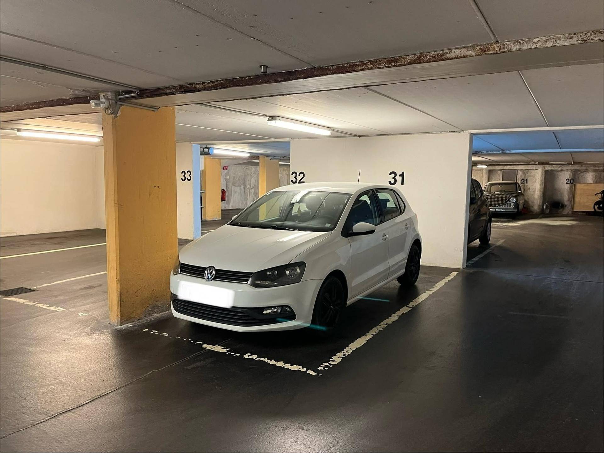 Weißes Auto parkt auf einem markierten Stellplatz in der Tiefgarage.