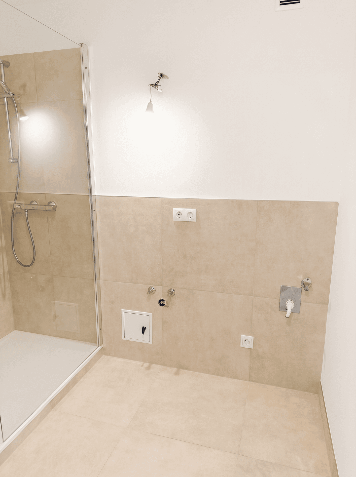 Modernes Badezimmer mit begehbarer Dusche und beigefarbenen Fliesen, bereit zur Installation.