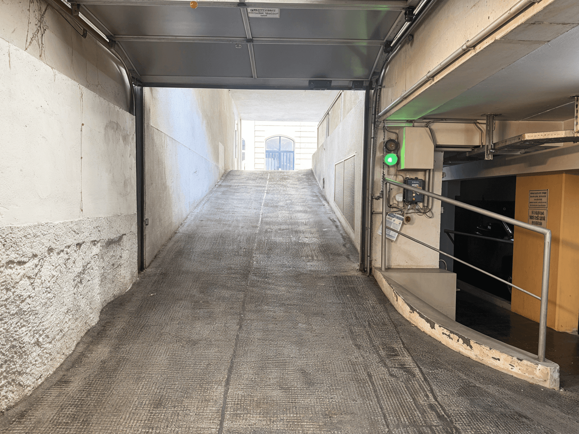 Ausfahrt einer Tiefgarage mit Rampe, die ins Freie führt.