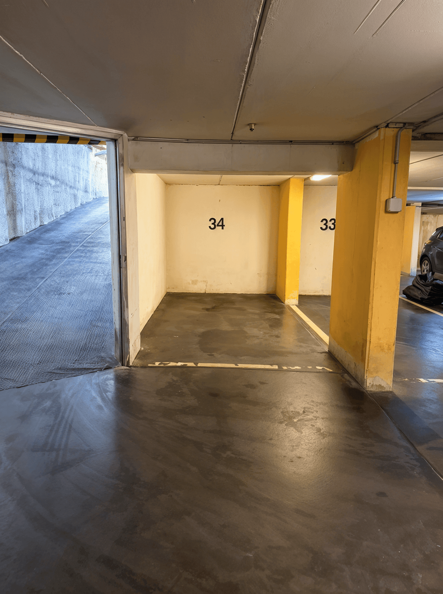 Leerer Tiefgaragenstellplatz Nummer 34 mit Zugang zur Einfahrtsrampe, hell und geräumig.