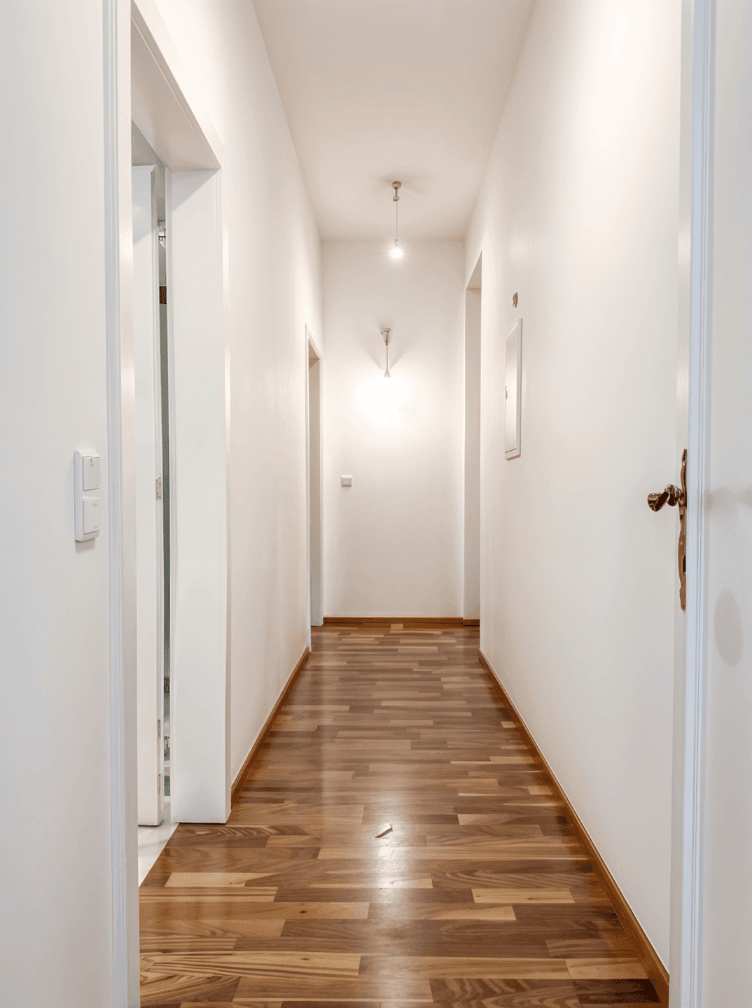 Langer, heller Flur mit Holzboden, der verschiedene Räume miteinander verbindet.