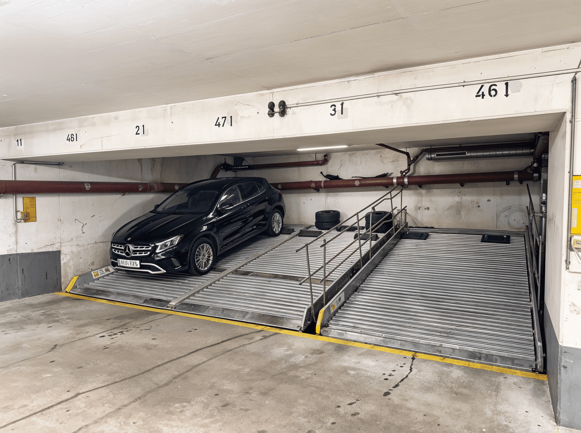 Detailansicht einer schwarzen Limousine auf einer Autohebebühne in der Tiefgarage.