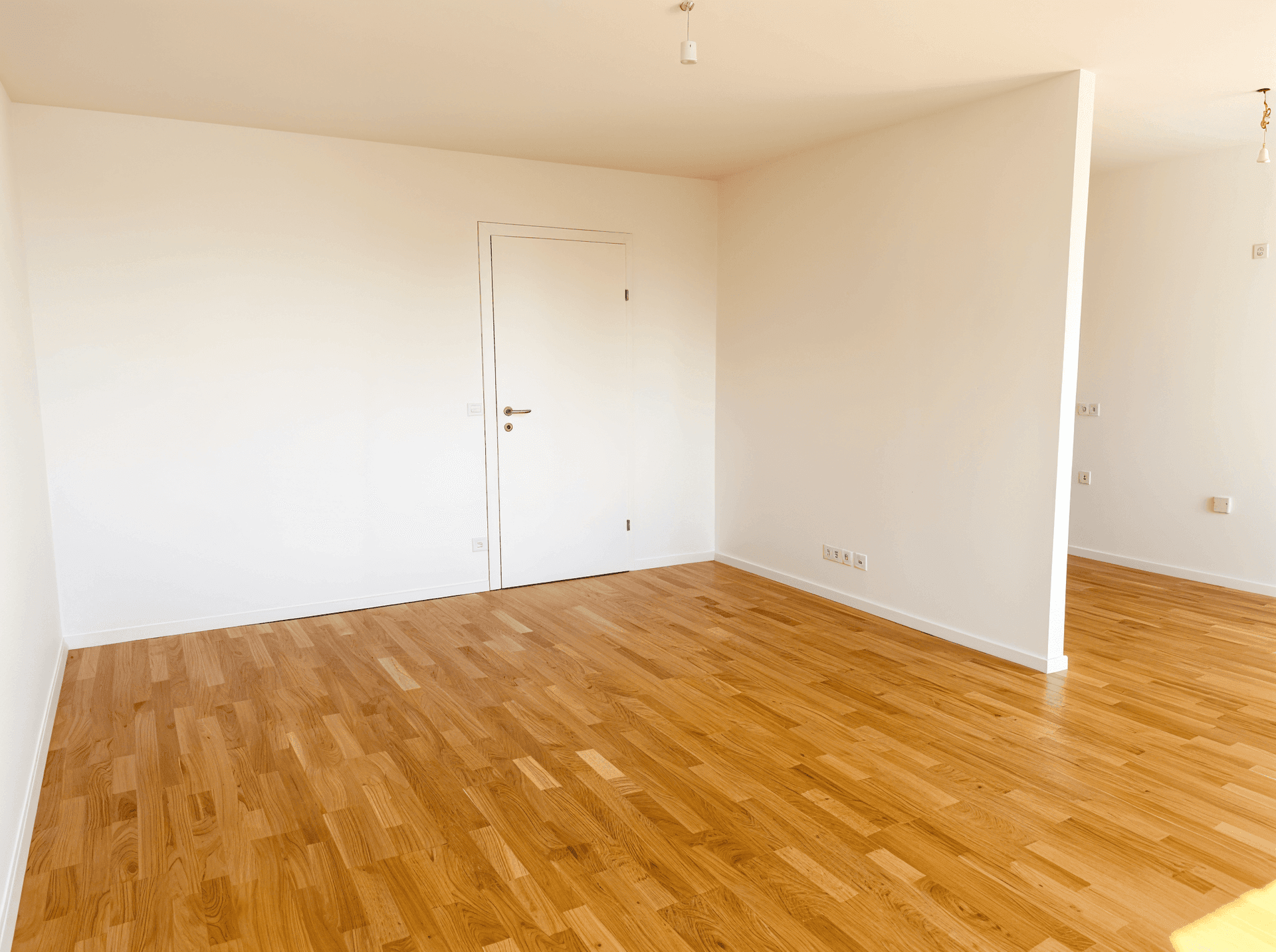Heller, leerer Raum mit Holzboden und weiß gestrichenen Wänden, ideal für individuelle Gestaltung.