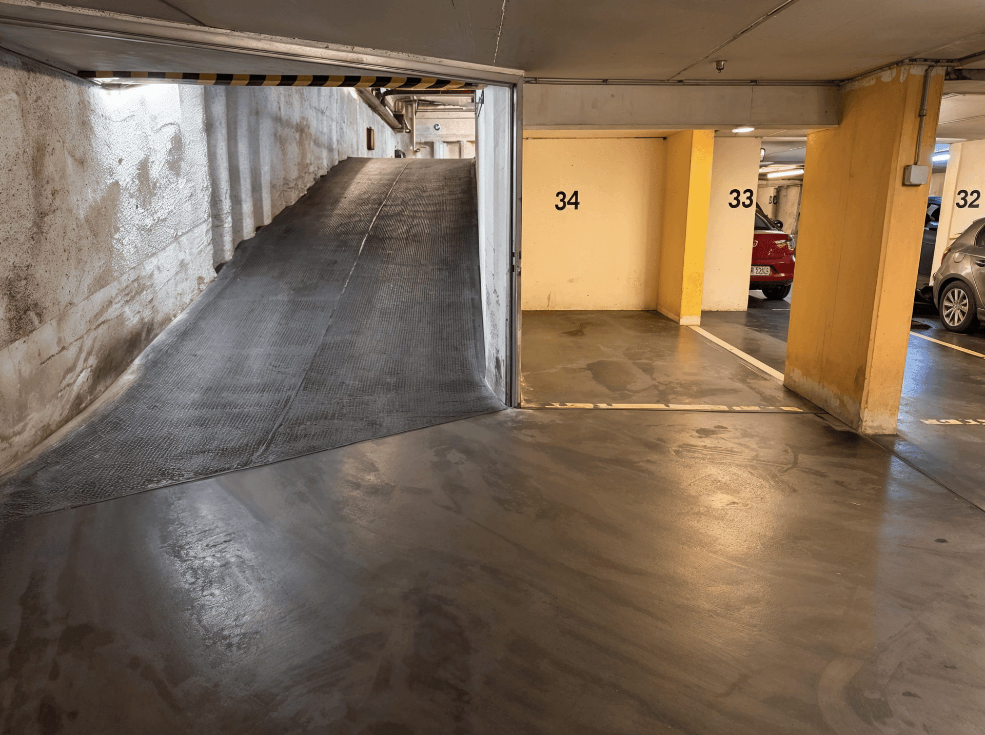 Ausfahrt einer Tiefgarage mit Rampe und leeren Stellplätzen.