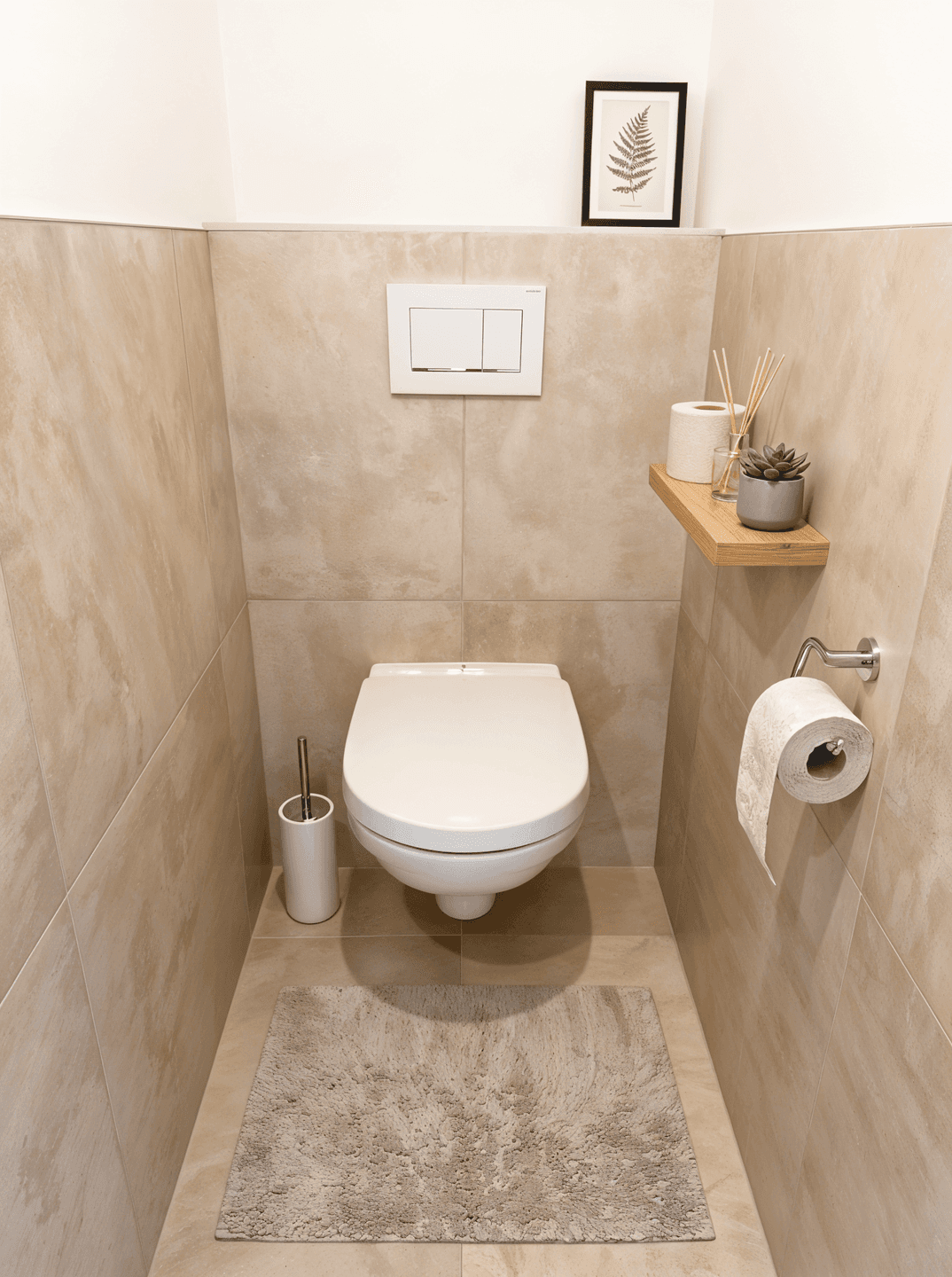 Separates WC mit Wand-WC, beigefarbenen Fliesen und minimalistischer Dekoration.