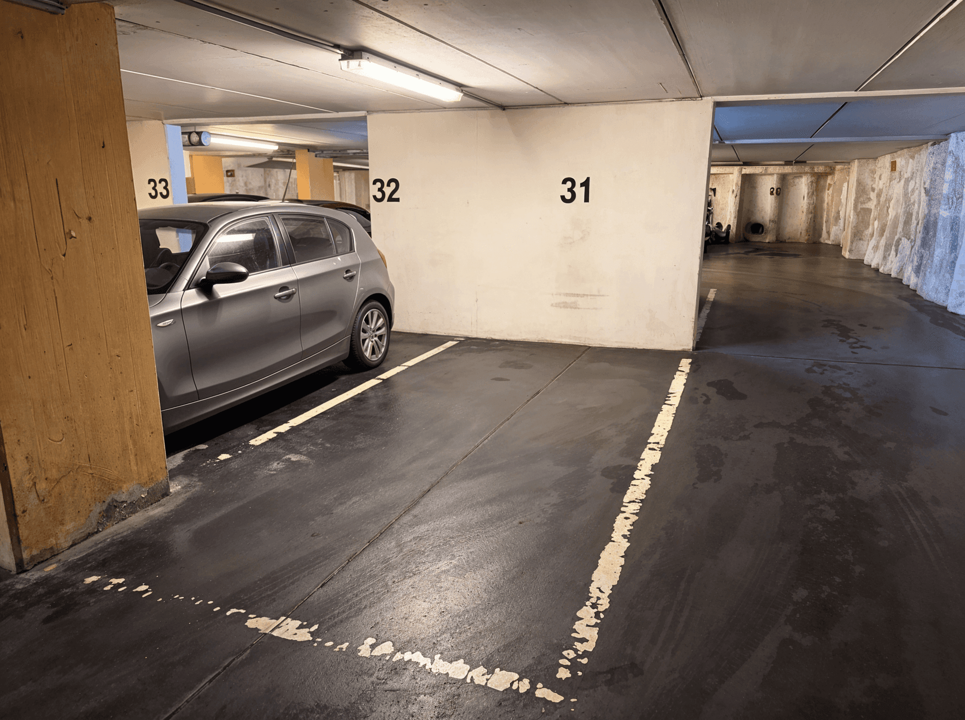 Tiefgarage mit nummerierten Stellplätzen und einem geparkten Fahrzeug.