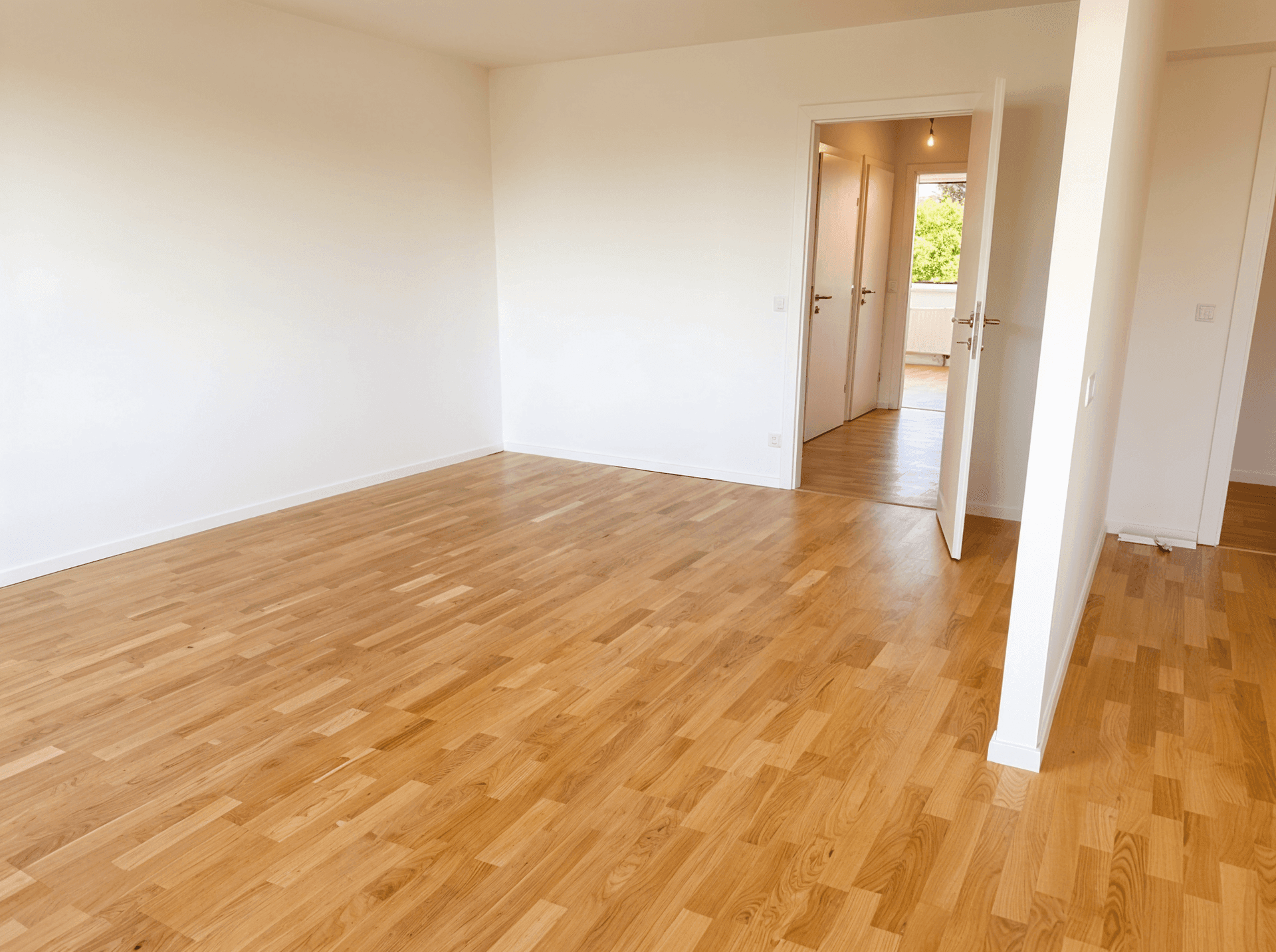Geräumiger, leerer Raum mit Holzboden und mehreren Türen zu angrenzenden Zimmern.