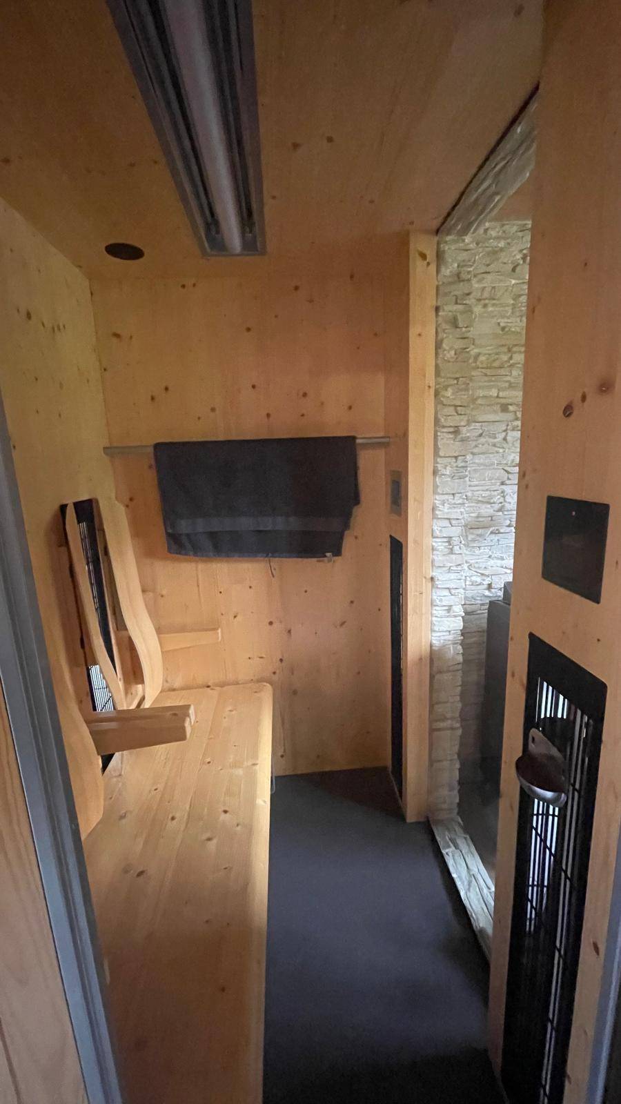 Moderne Infrarotkabine mit Holzbänken und Steinwand-Akzenten für Entspannung.