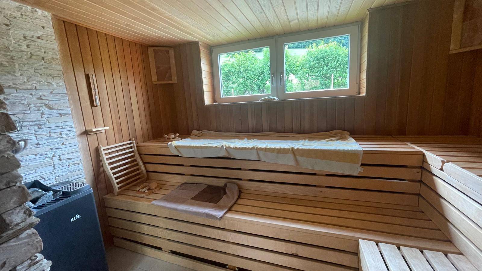 Geräumige Holzsauna mit mehreren Bänken und Fenster mit Blick ins Grüne.