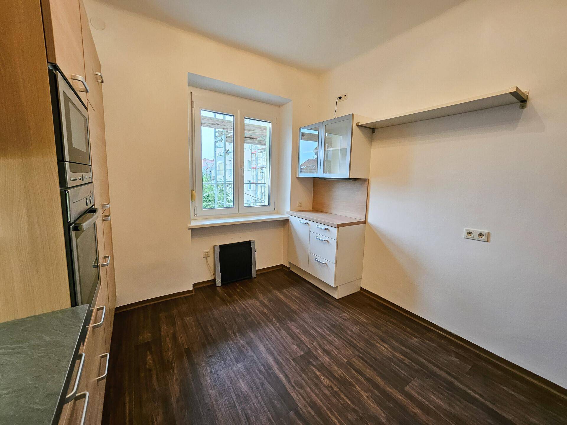 Küchenbereich mit Fenster, kleineren Einbauschränken und viel Platz für einen Esstisch.
