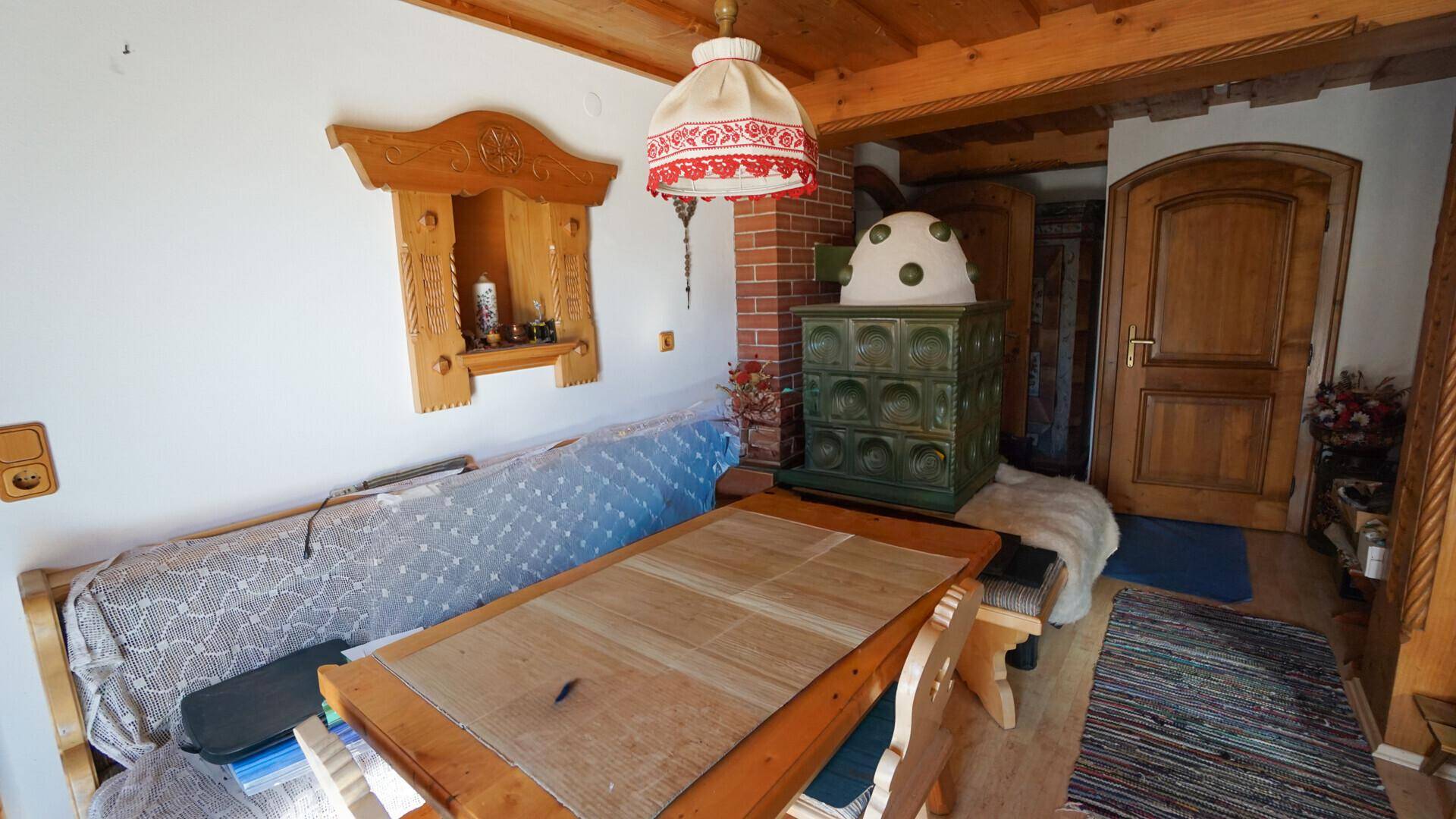 Gemütlicher Essbereich im alpinen Stil mit Holzbalkendecke, Kachelofen und traditionellen Möbeln.