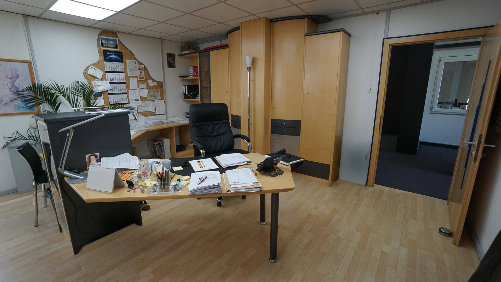 Funktionales Büro mit Holzmöbeln, Schreibtisch und Laminatboden, bereit für den Arbeitsalltag.