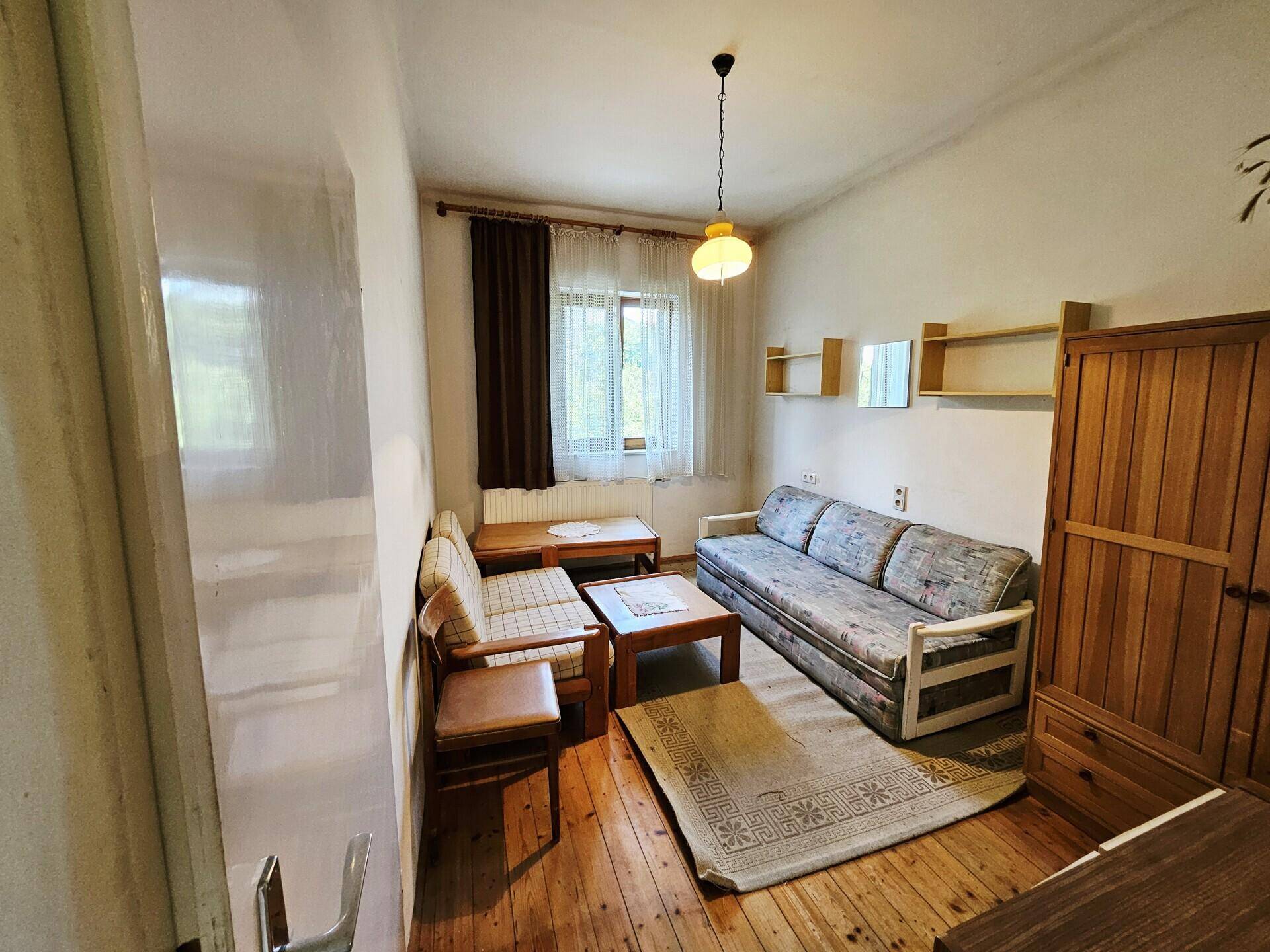 Helles Wohnzimmer mit Holzfußboden, bequemen Sofas und einem Fenster mit Blick ins Grüne.