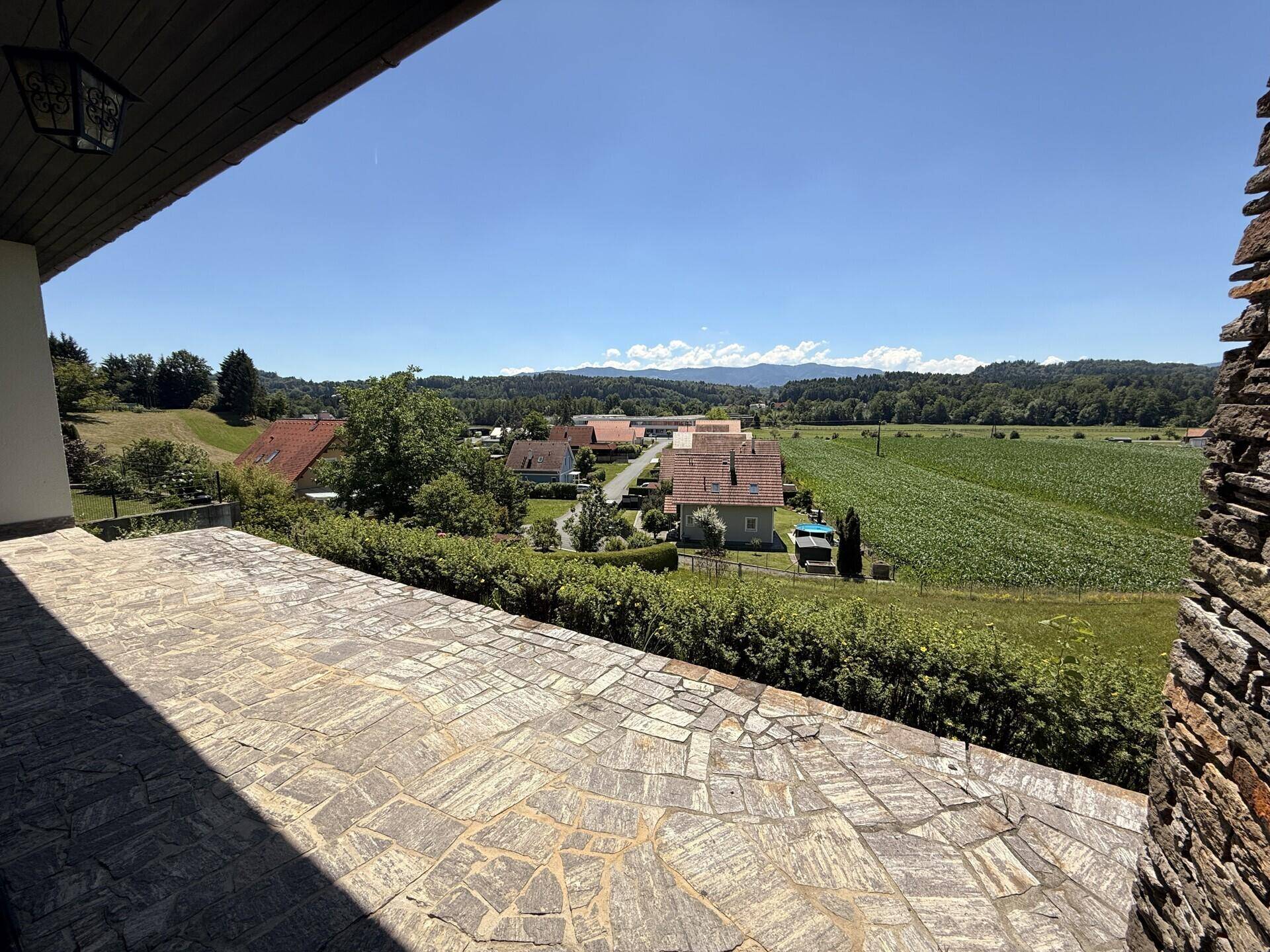 Große gepflasterte Terrasse mit weitem Blick über Felder und die umliegende Landschaft.