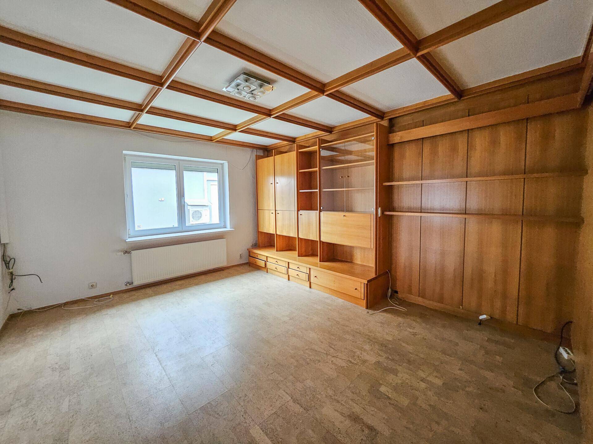 Geräumiges Wohnzimmer mit Korkboden, Holzdecke und großer Schrankwand.