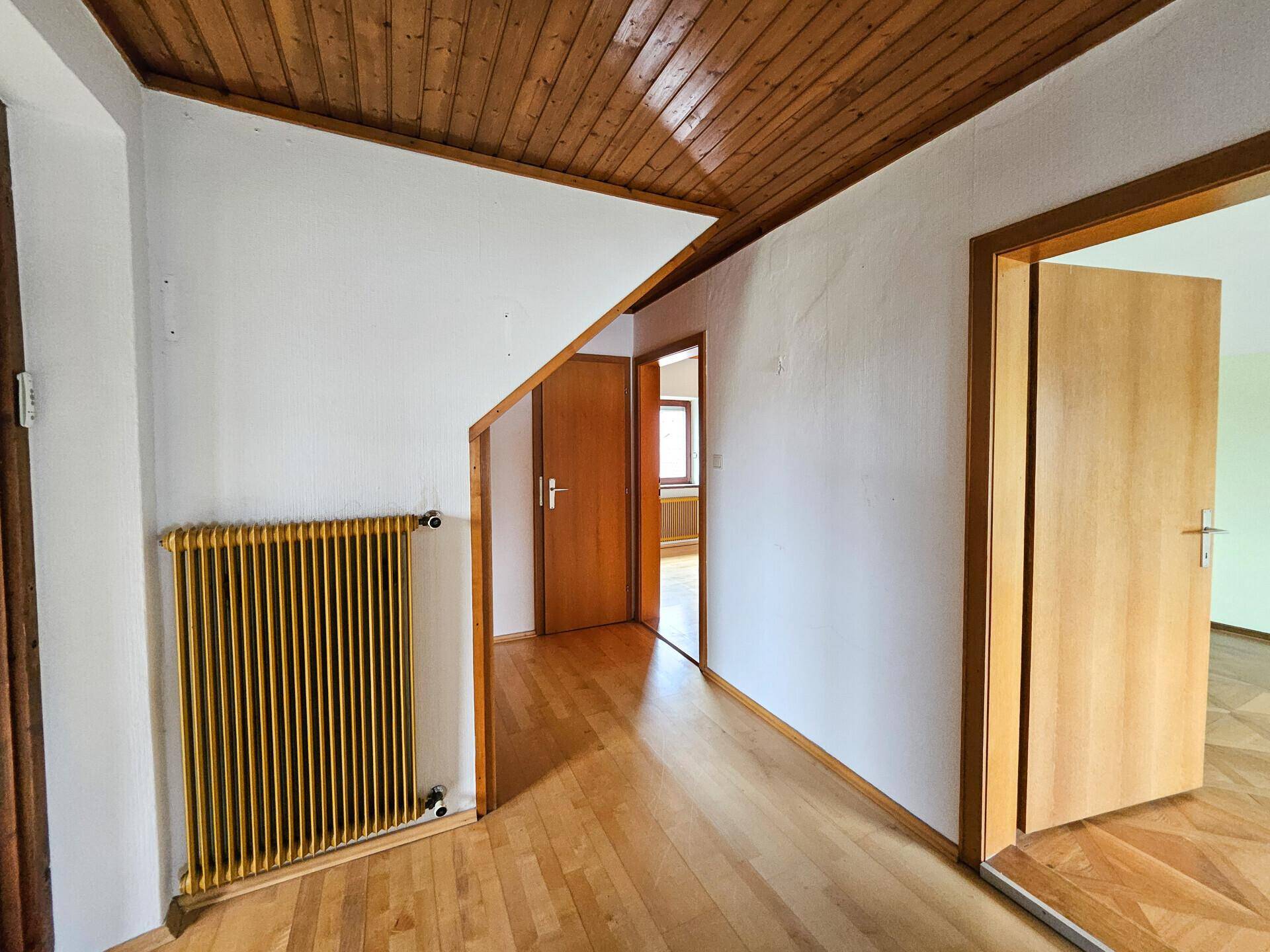 Heller Flur mit Holzparkett, Holzdecke und Heizkörper im Landhausstil.