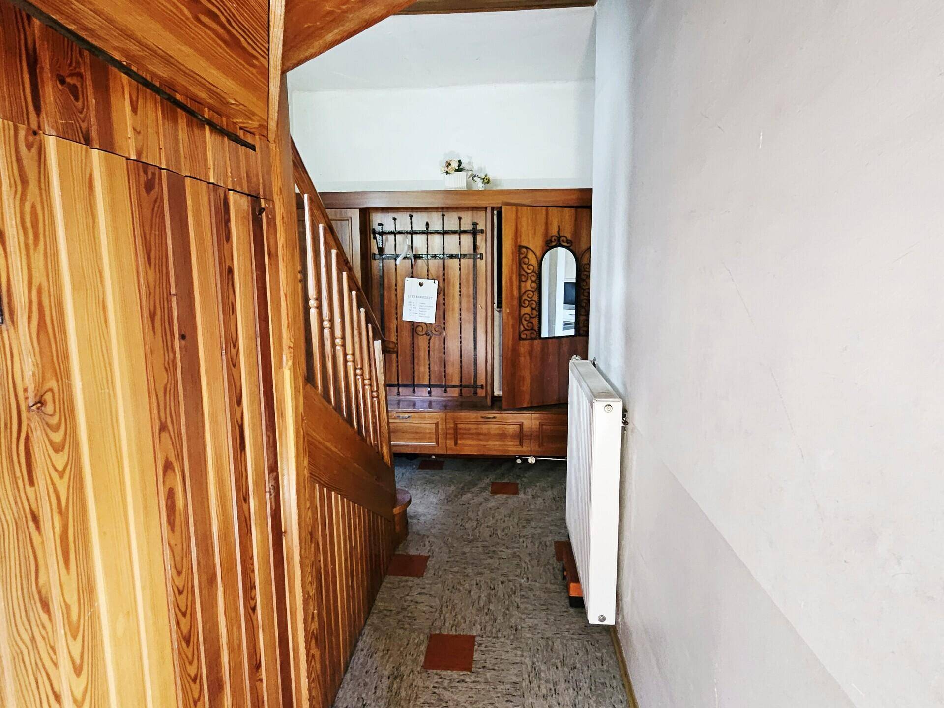 Eingangsbereich mit Holzvertäfelung, Treppe und traditioneller Garderobe.