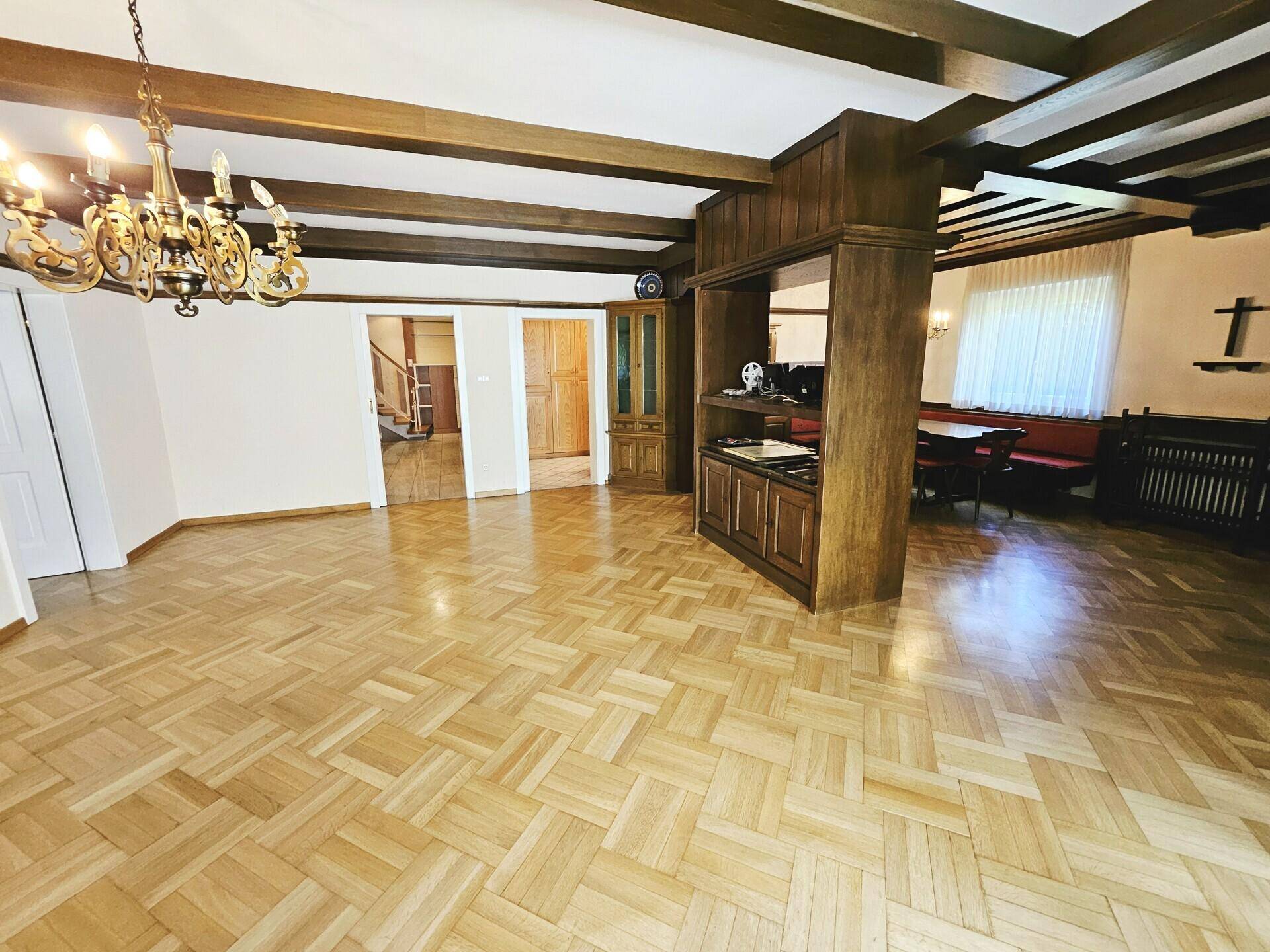 Offener Wohnbereich mit Parkettboden, Holzbalkendecke und Übergang zum Esszimmer.