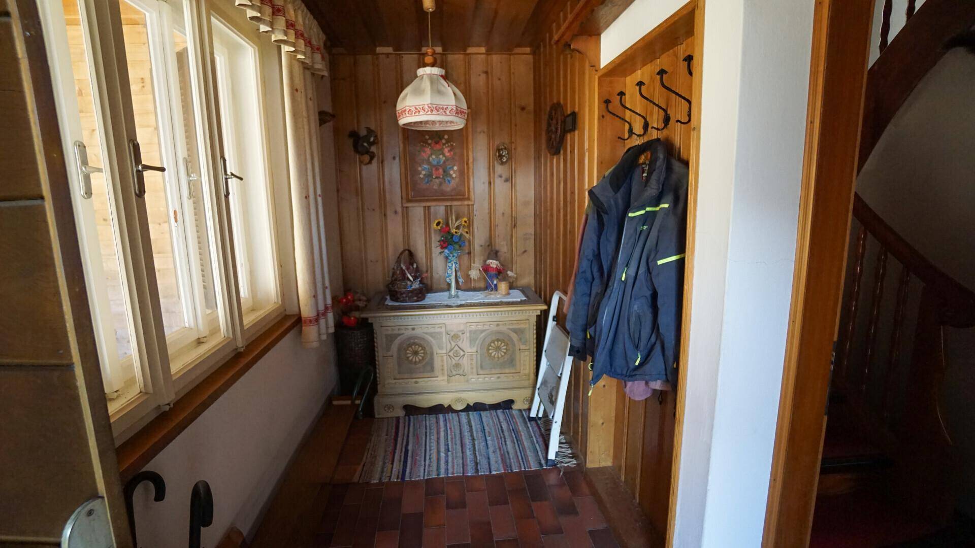 Eingangsbereich im Landhausstil mit Holzvertäfelung, Garderobe und traditioneller Truhe.