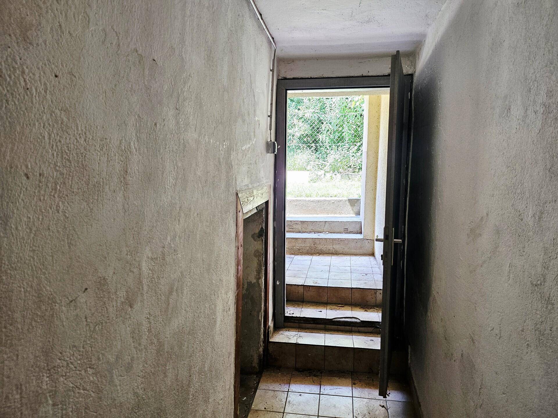 Kellerraum mit Zugang nach draußen über eine Steintreppe und Fliesenboden.