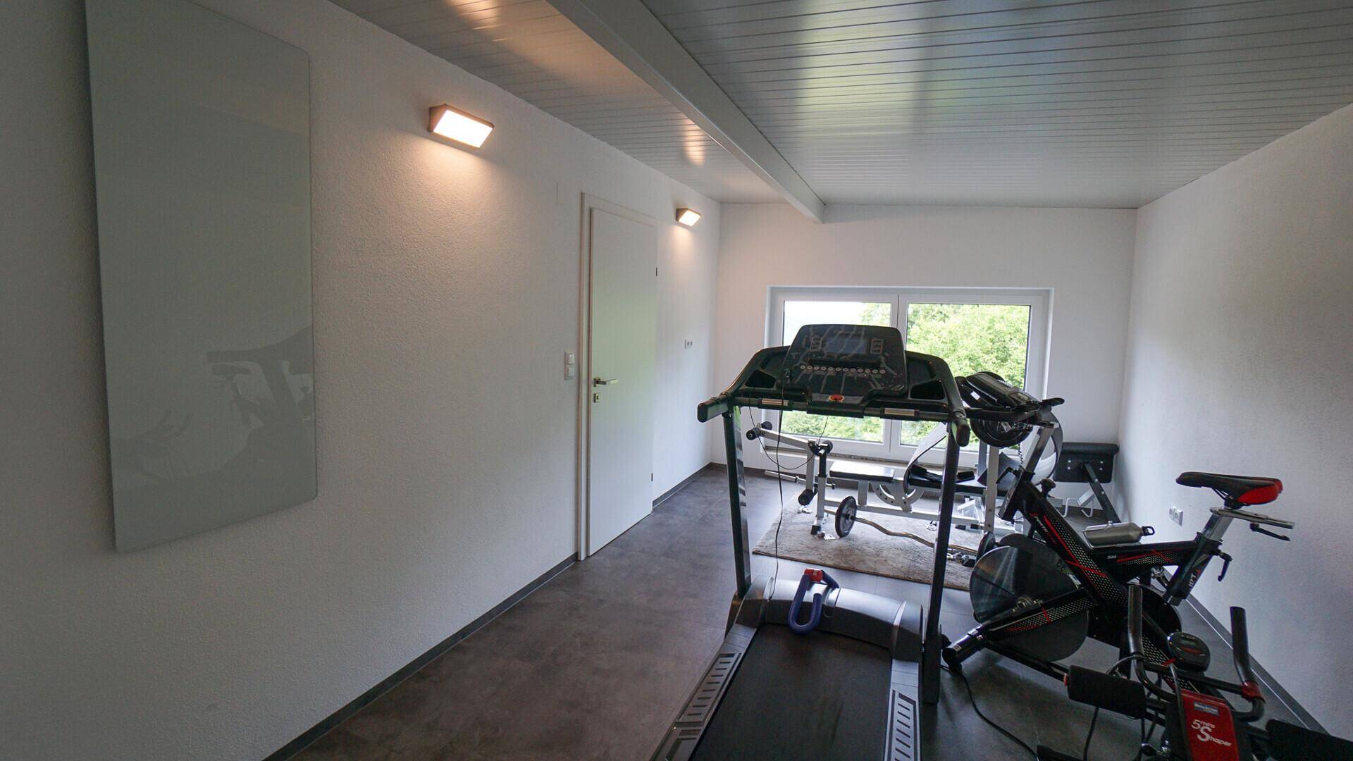 Heller Fitnessraum mit Laufband und Trainingsgeräten, ideal für das tägliche Workout.