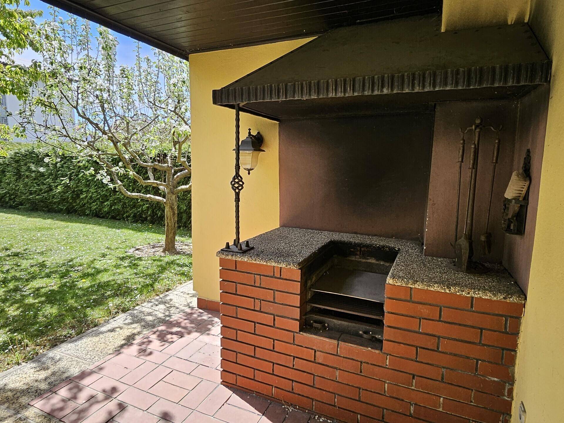 Gemauerter Grillplatz mit Überdachung und gepflastertem Bereich im Garten.
