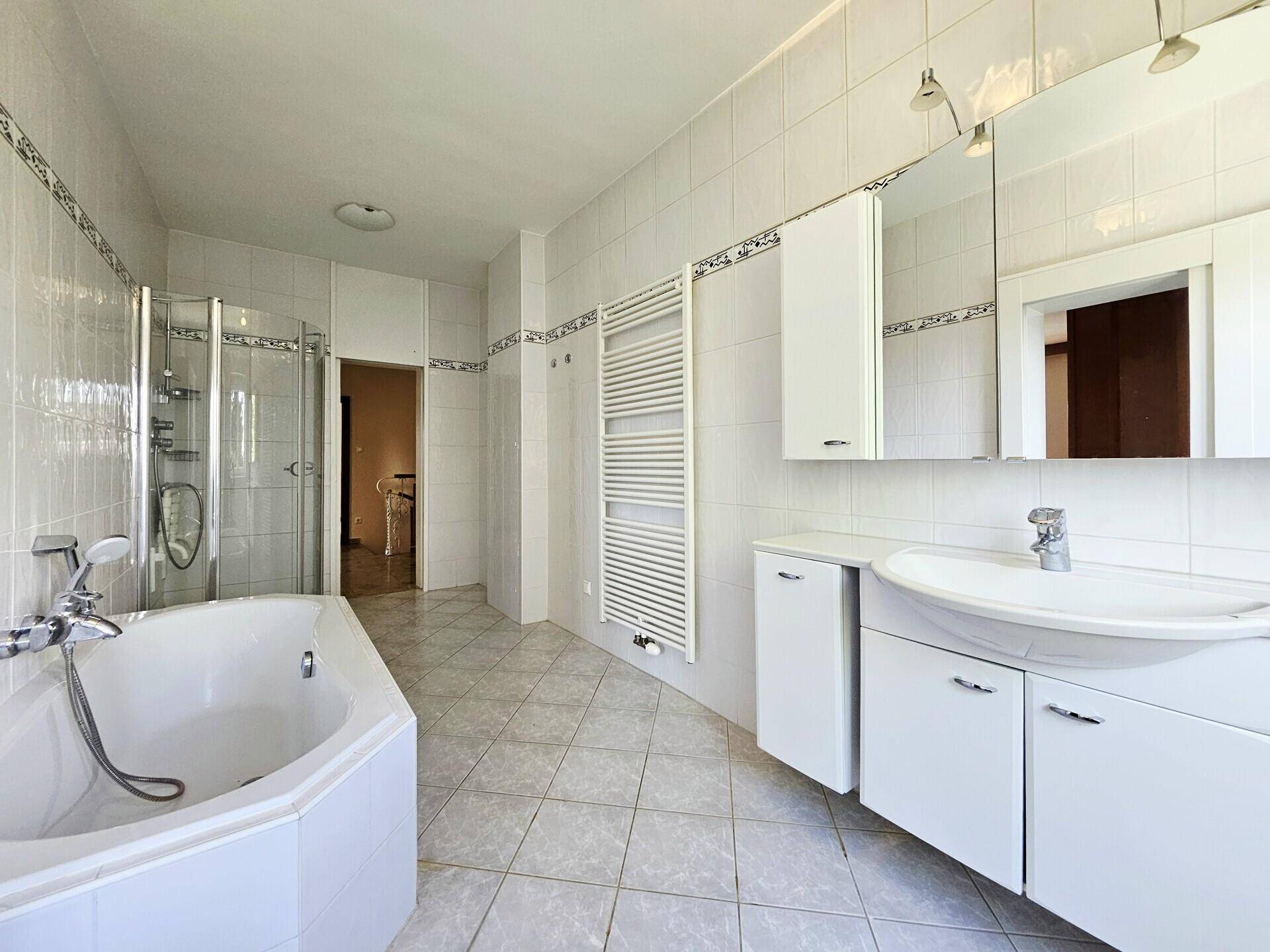 Geräumiges Badezimmer mit Badewanne, Duschkabine, Einzelwaschbecken und weißen Fliesen.
