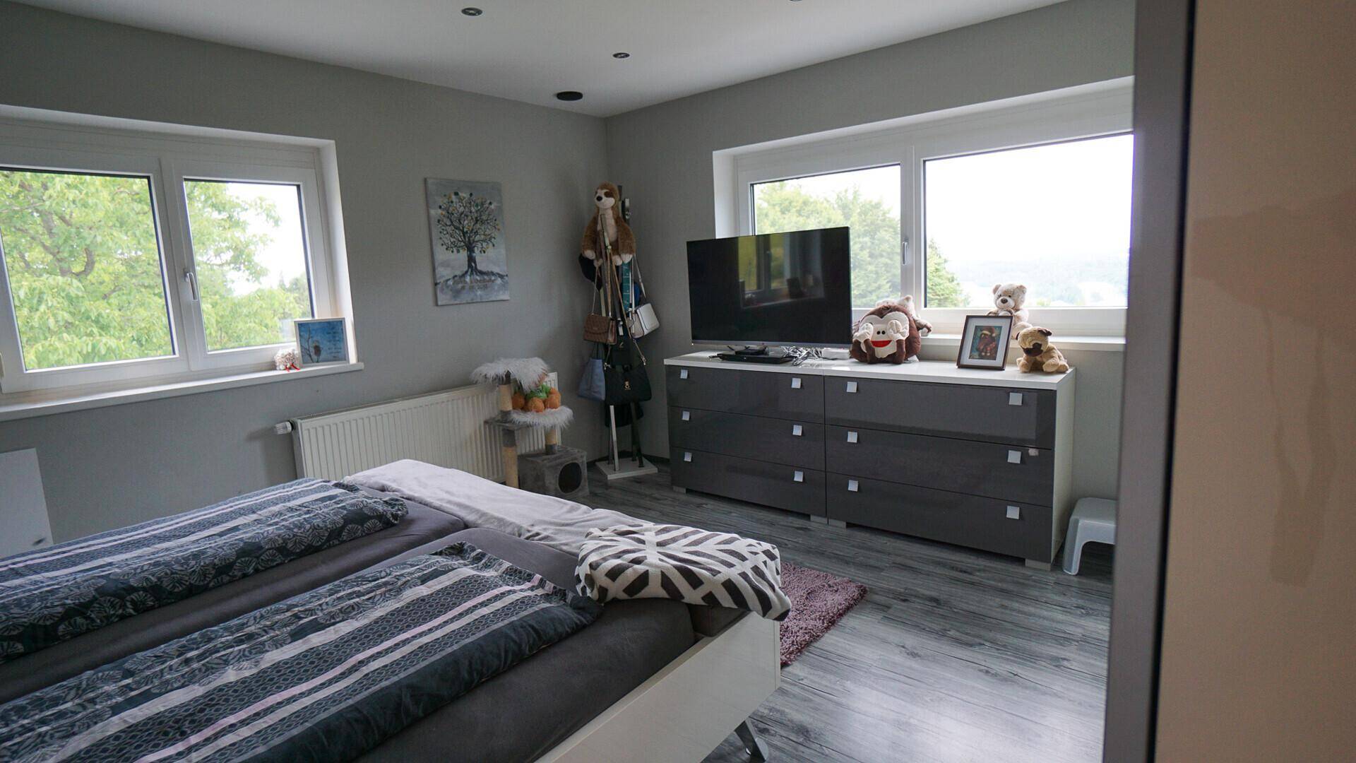 Geräumiges Schlafzimmer mit Doppelbett, Kommode und großen Fenstern mit Weitblick.