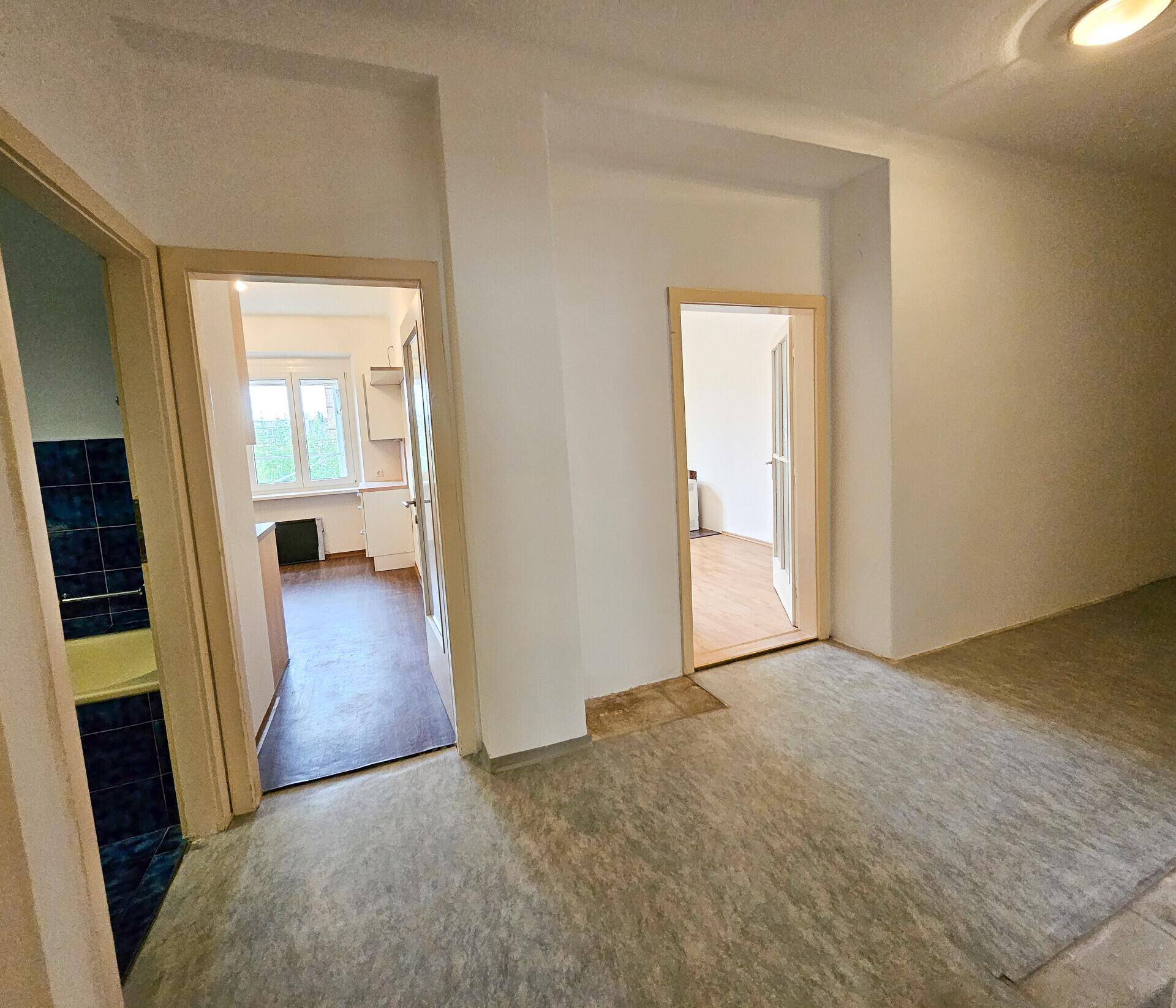 Zentraler Flur mit Zugang zu Küche und weiteren Zimmern, mit Renovierungsbedarf.