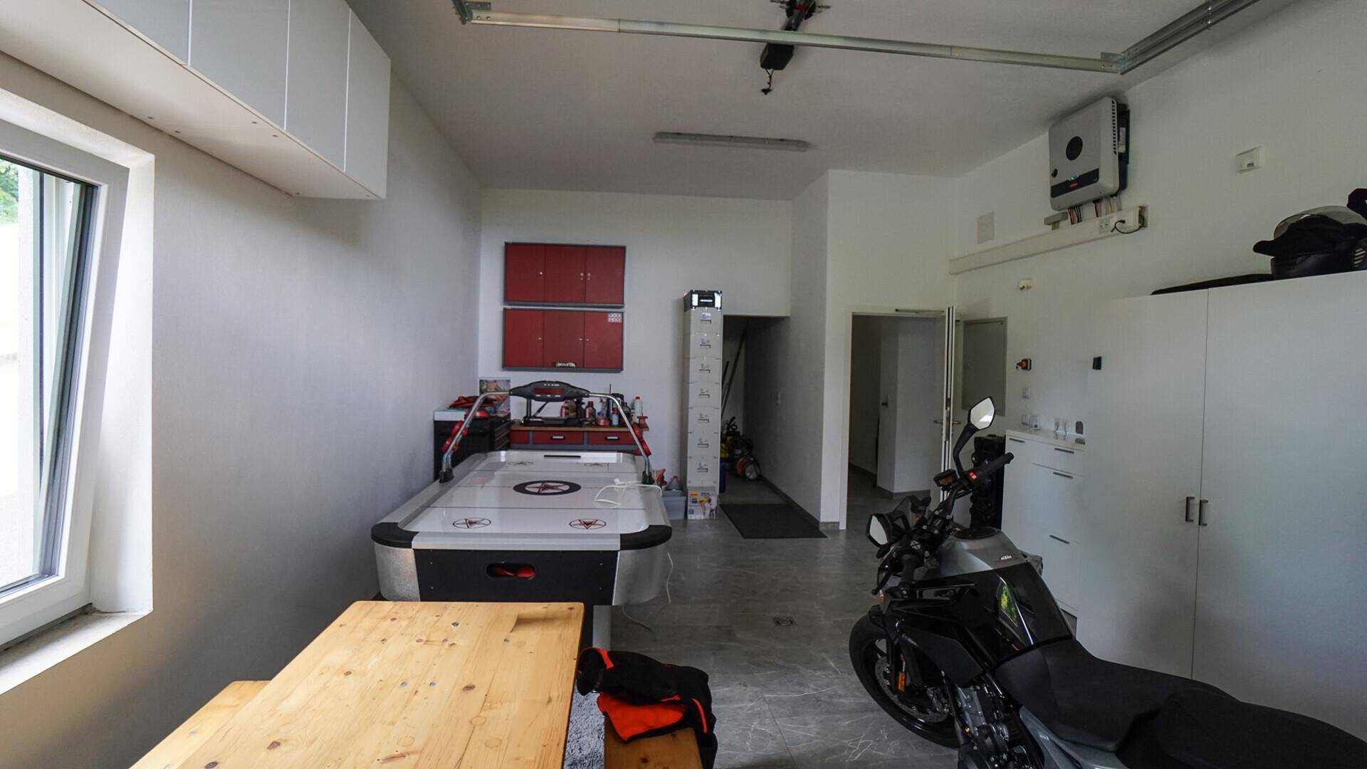 Geräumige Garage mit viel Stauraum, Motorrad und Airhockey-Tisch, auch als Hobbyraum nutzbar.