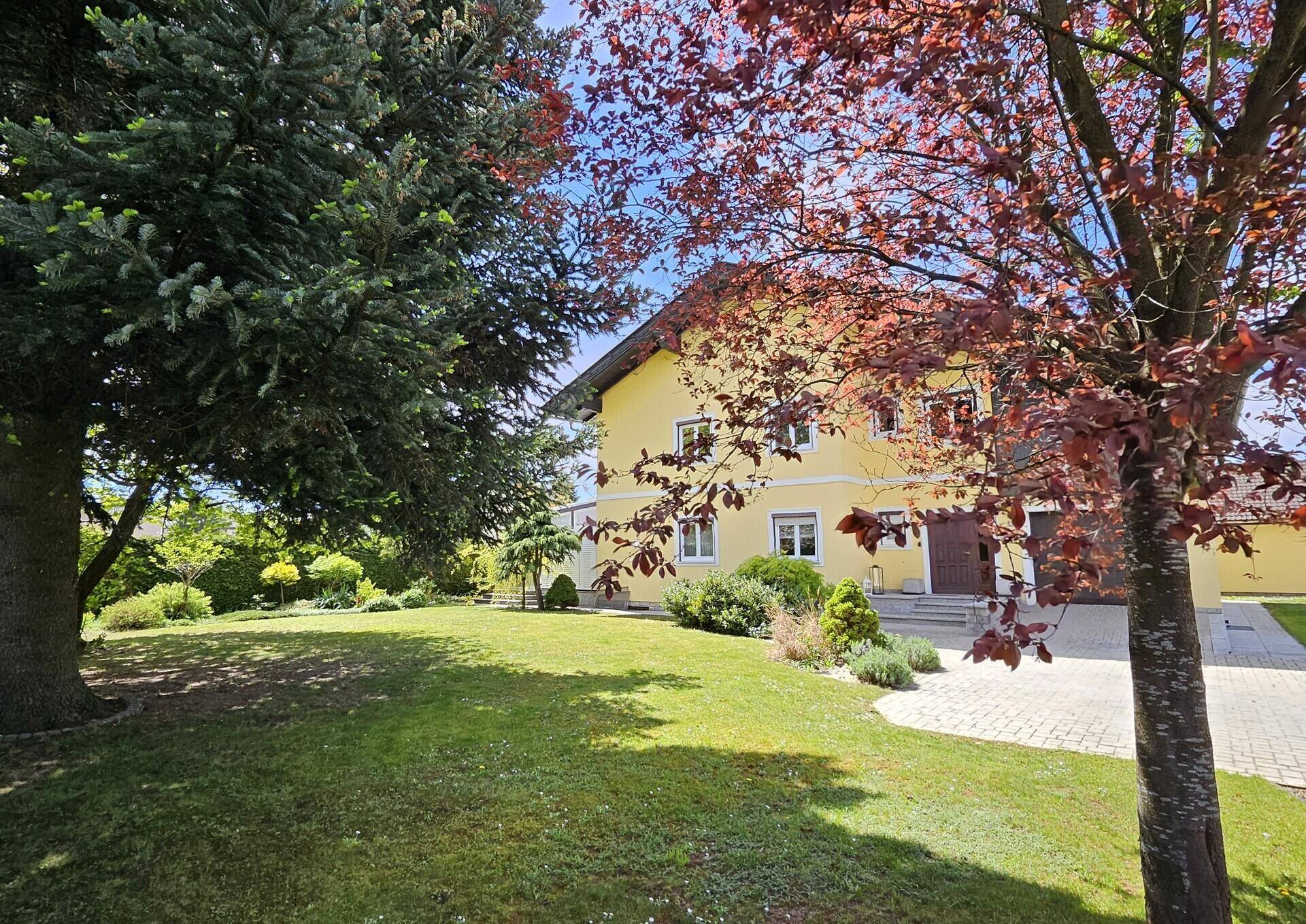 Weitläufiger Garten mit verschiedenen Bäumen und Sträuchern vor dem Haus.