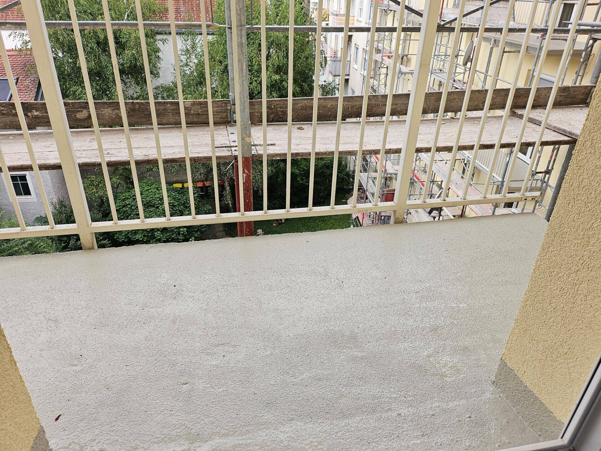 Balkon mit Blick auf den Innenhof, umgeben von Baugerüsten, die auf Renovierung hindeuten.